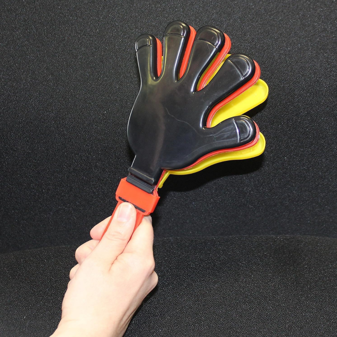 Eine Hand hält einen schwarzen, roten und gelben Handklatschen vor schwarzem Hintergrund.