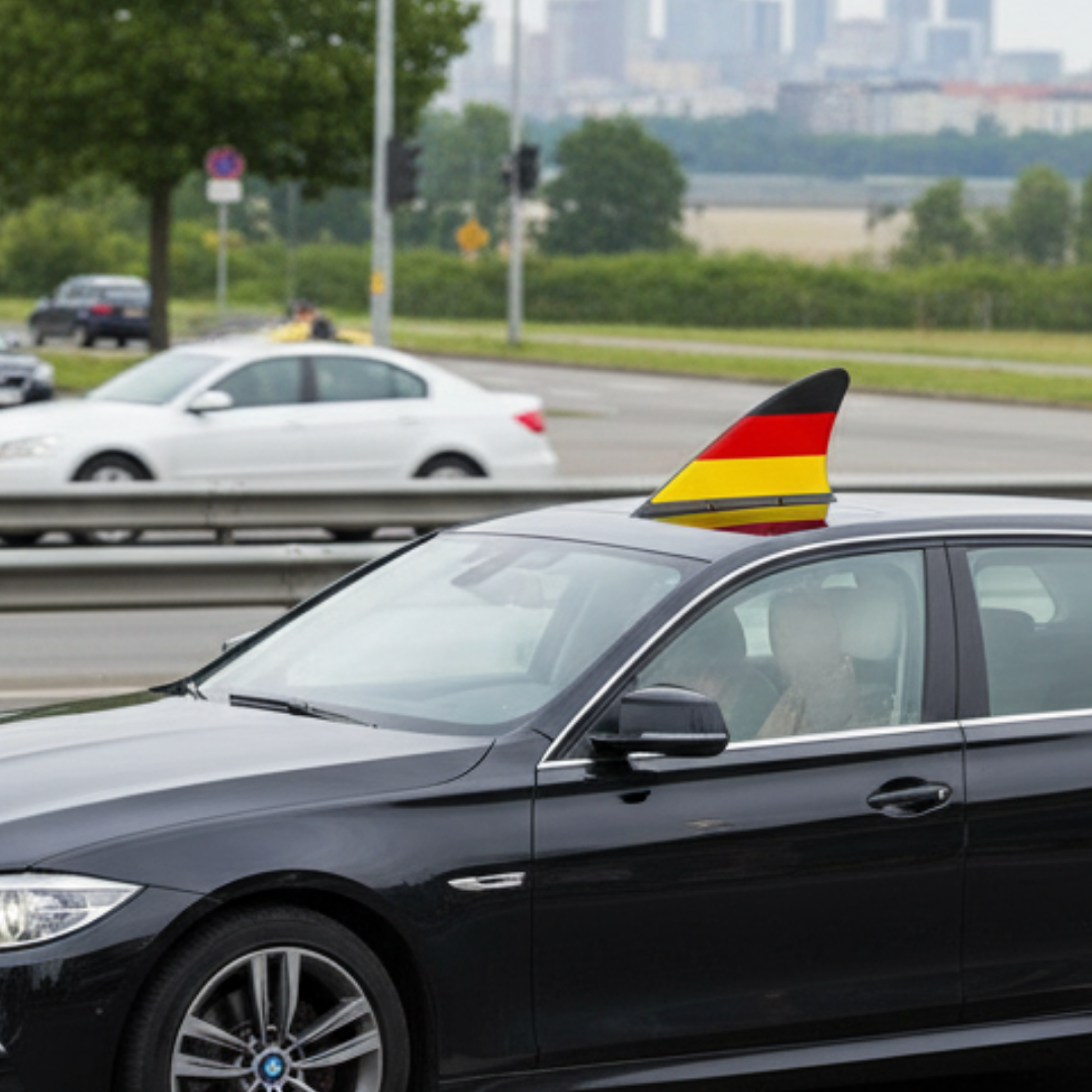 Ein schwarzes Auto fährt auf einer Straße mit einer deutschen Flagge auf dem Dach.