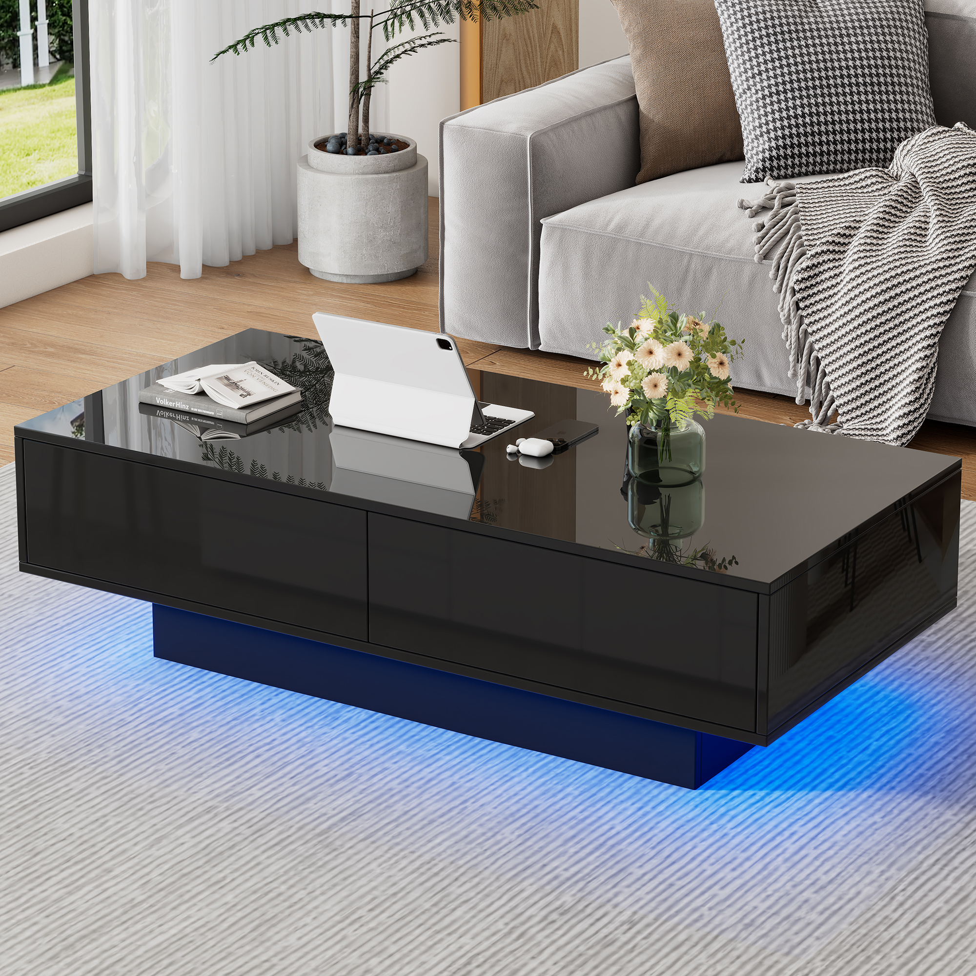 Schwarzer Couchtisch mit LED-Beleuchtung, Tablet, Handy, Kopfhörern und Blumen.