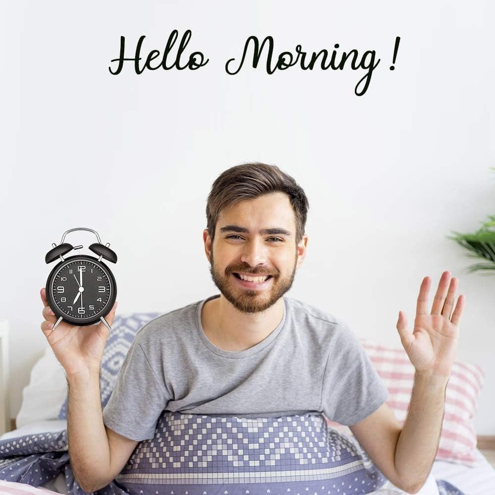 Mann hält Wecker, winkt lächelnd vom Bett aus. Text: Hello Morning!