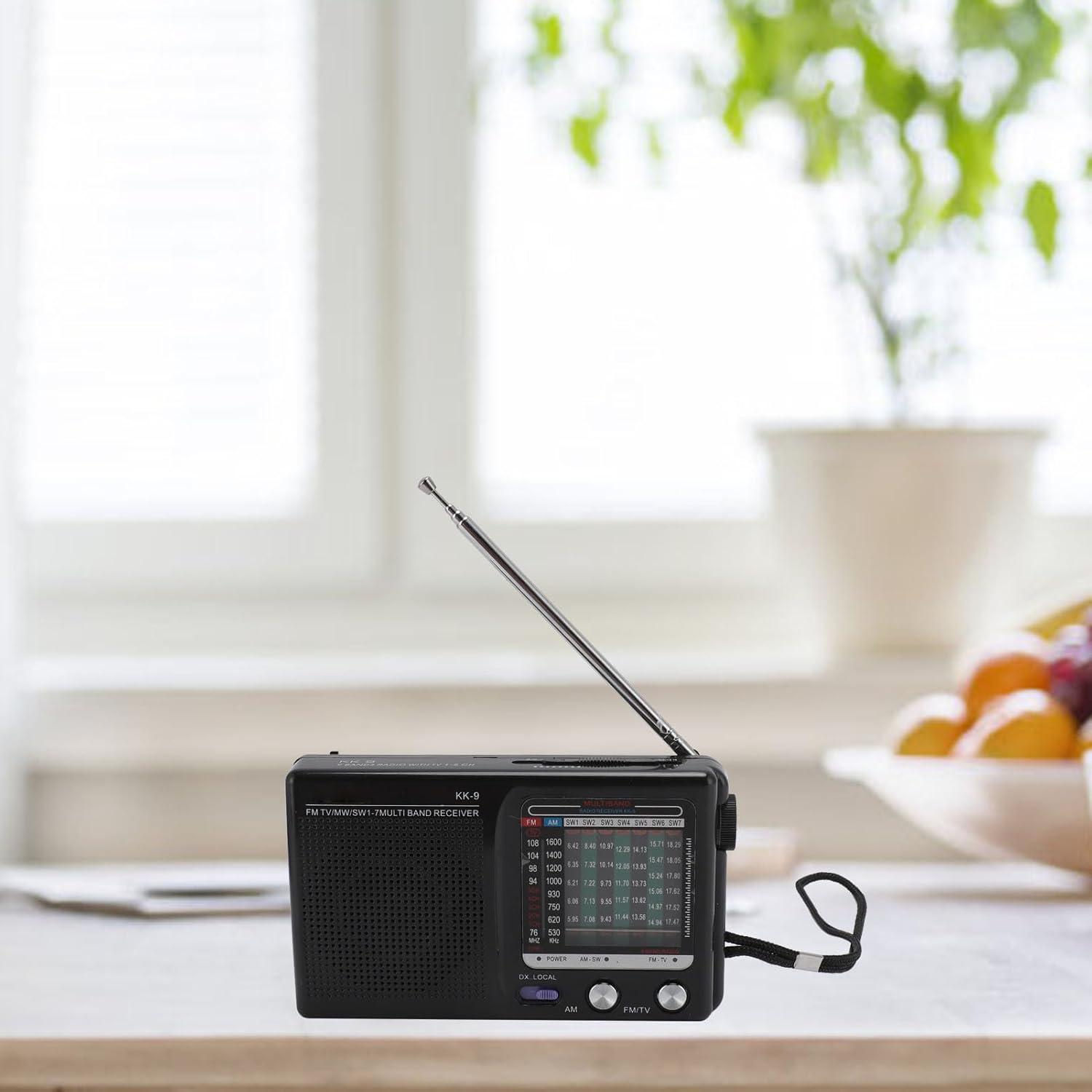 Ein schwarzes Radio mit Antenne auf einem Tisch, mit unscharfem Hintergrund.