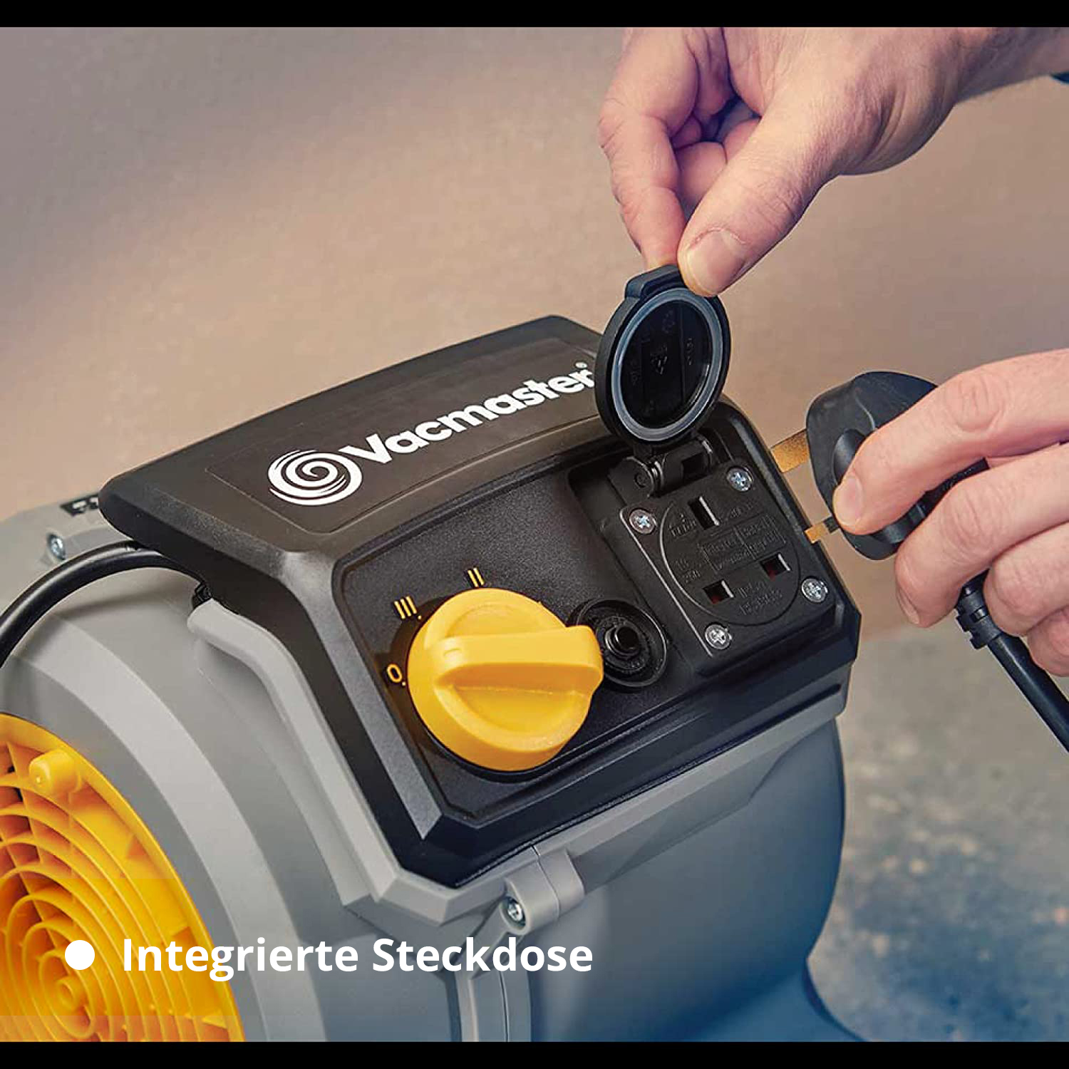 Eine Hand steckt einen Stecker in eine integrierte Steckdose am Gerät.