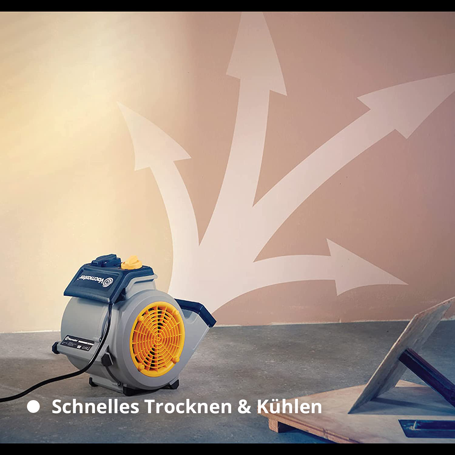 Grauer Ventilator mit gelbem Lüftergitter vor Wand mit weißen Pfeilen.