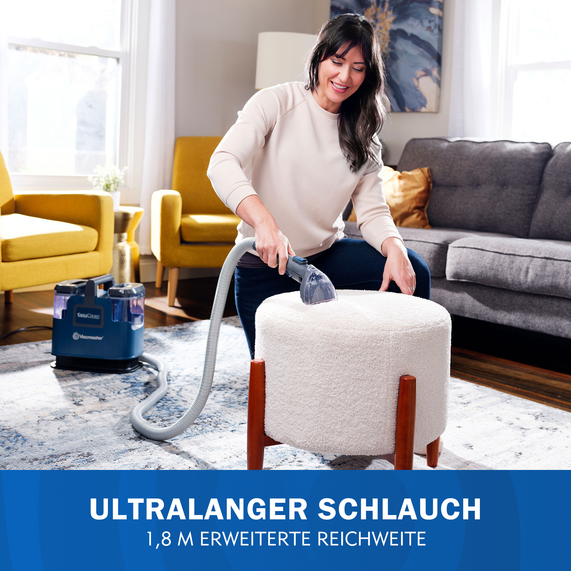 Frau reinigt Hocker mit Gerät. Blaue Maschine mit Schlauch im Wohnzimmer.