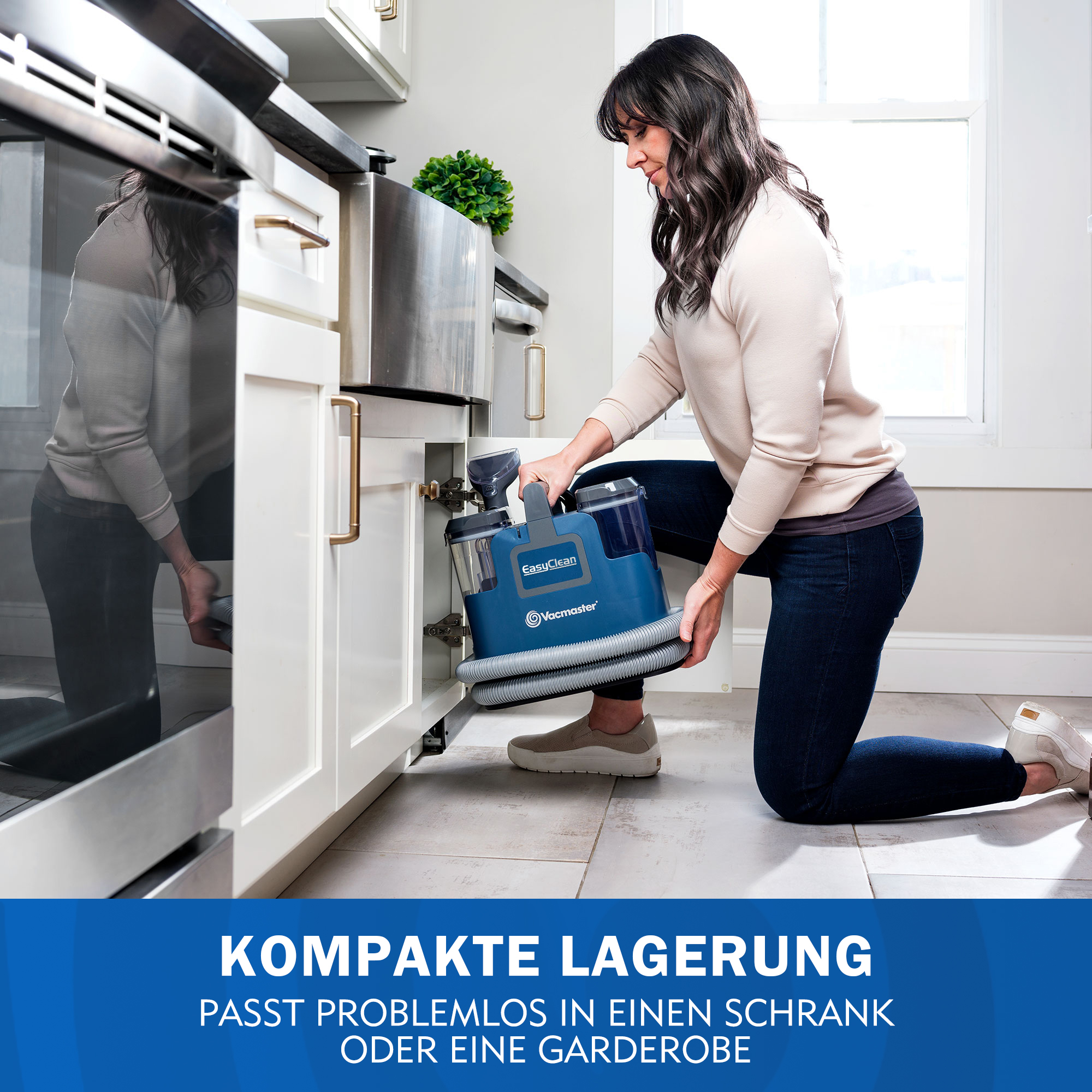 Frau verstaut blauen Nass-/Trockensauger in Küchenschrank.