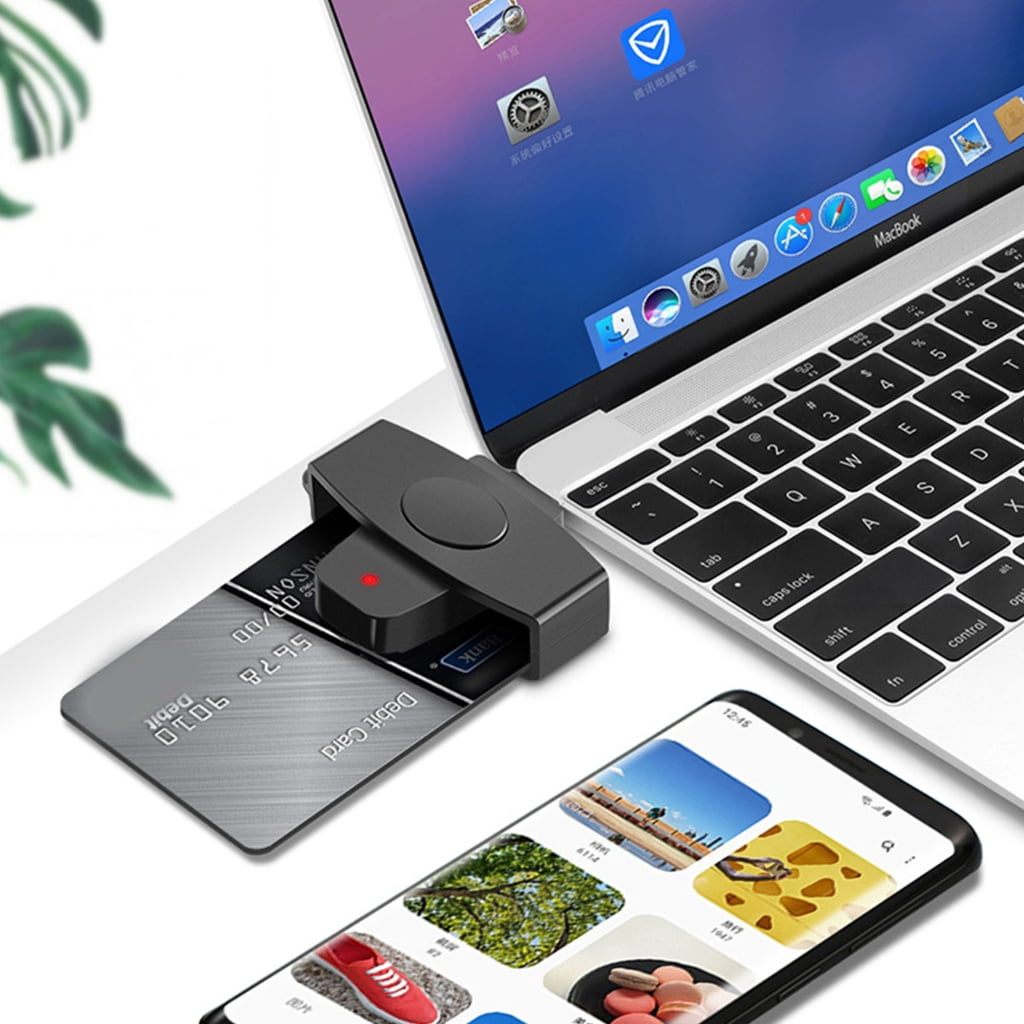 Eine Debitkarte wird in ein Kartenlesegerät gesteckt, das an ein MacBook angeschlossen ist. Ein Smartphone zeigt Bilder an.