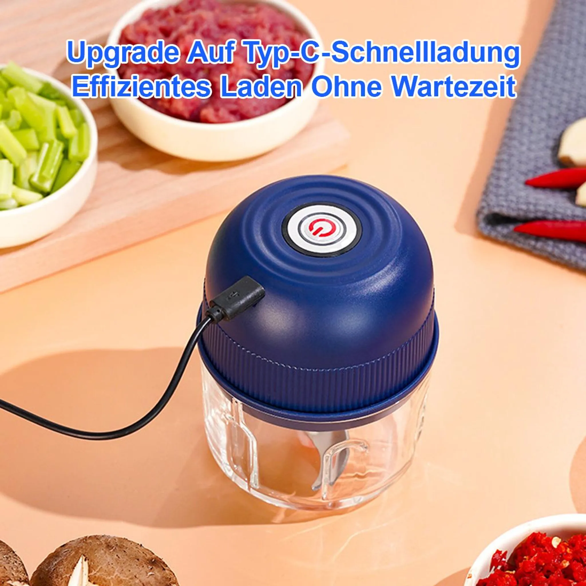 Ein blauer Mini-Zerkleinerer mit USB-Kabel, neben Schüsseln mit gehacktem Gemüse und Fleisch.