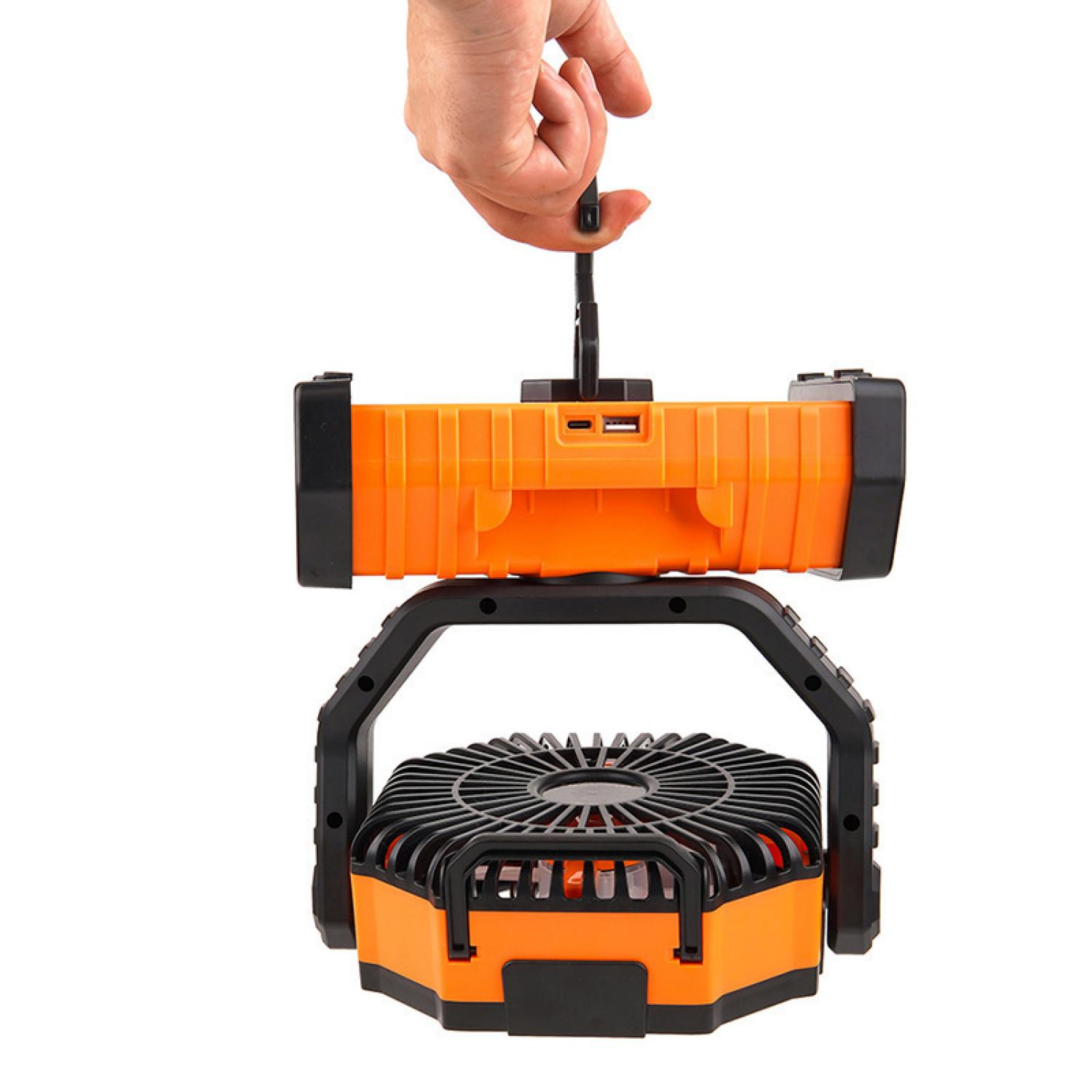 Eine Hand hält einen orangefarbenen Akku-Ventilator mit integriertem Licht.