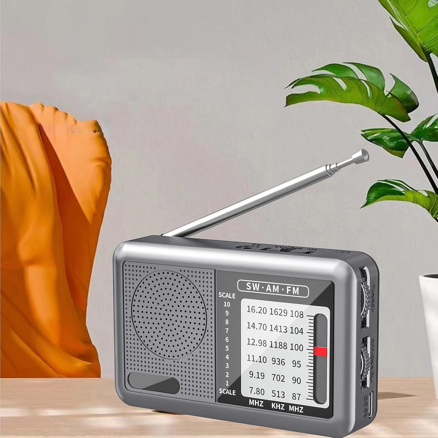 Ein silbernes tragbares Radio mit ausziehbarer Antenne steht auf einem Tisch.