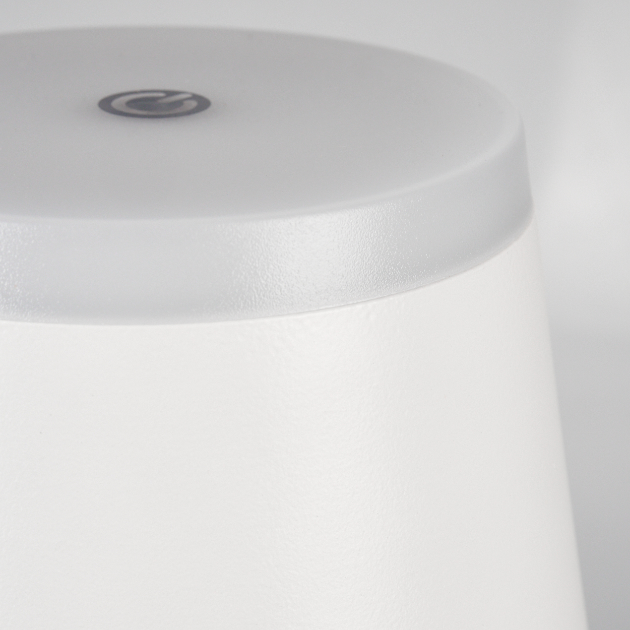 Nahaufnahme einer weißen Lampe mit einem matten Deckel und einem dezenten Logo.