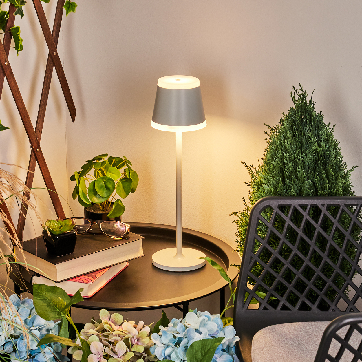 Ein graues Licht auf einem Tisch mit Büchern, Pflanzen und Blumen.