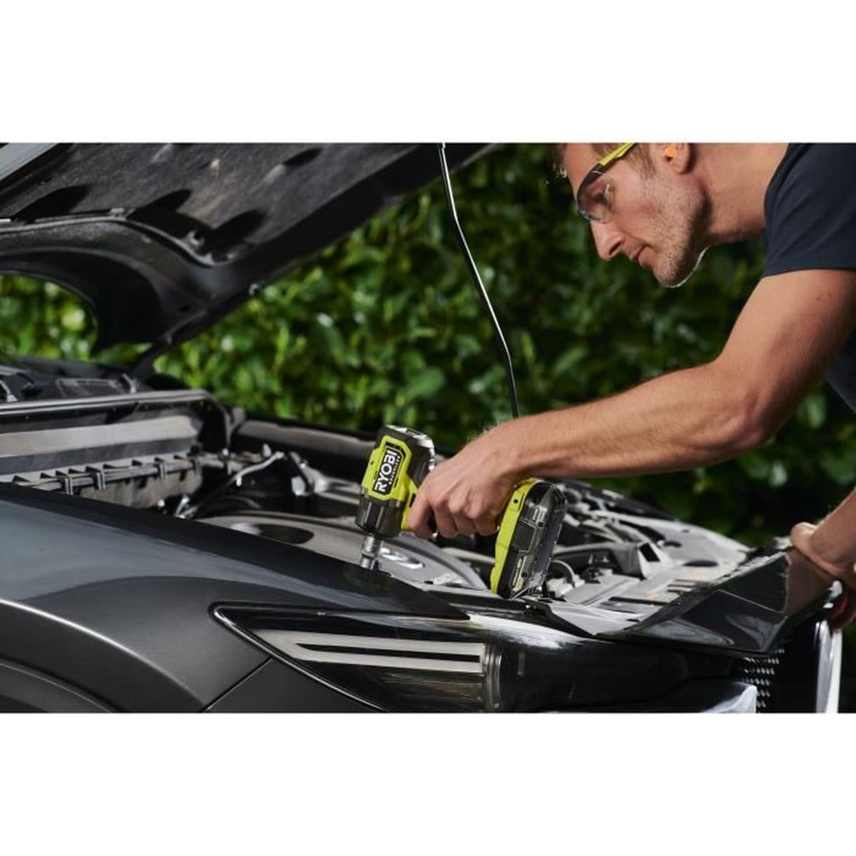 Mann mit Schutzbrille arbeitet mit Ryobi Schlagschrauber am Automotor.