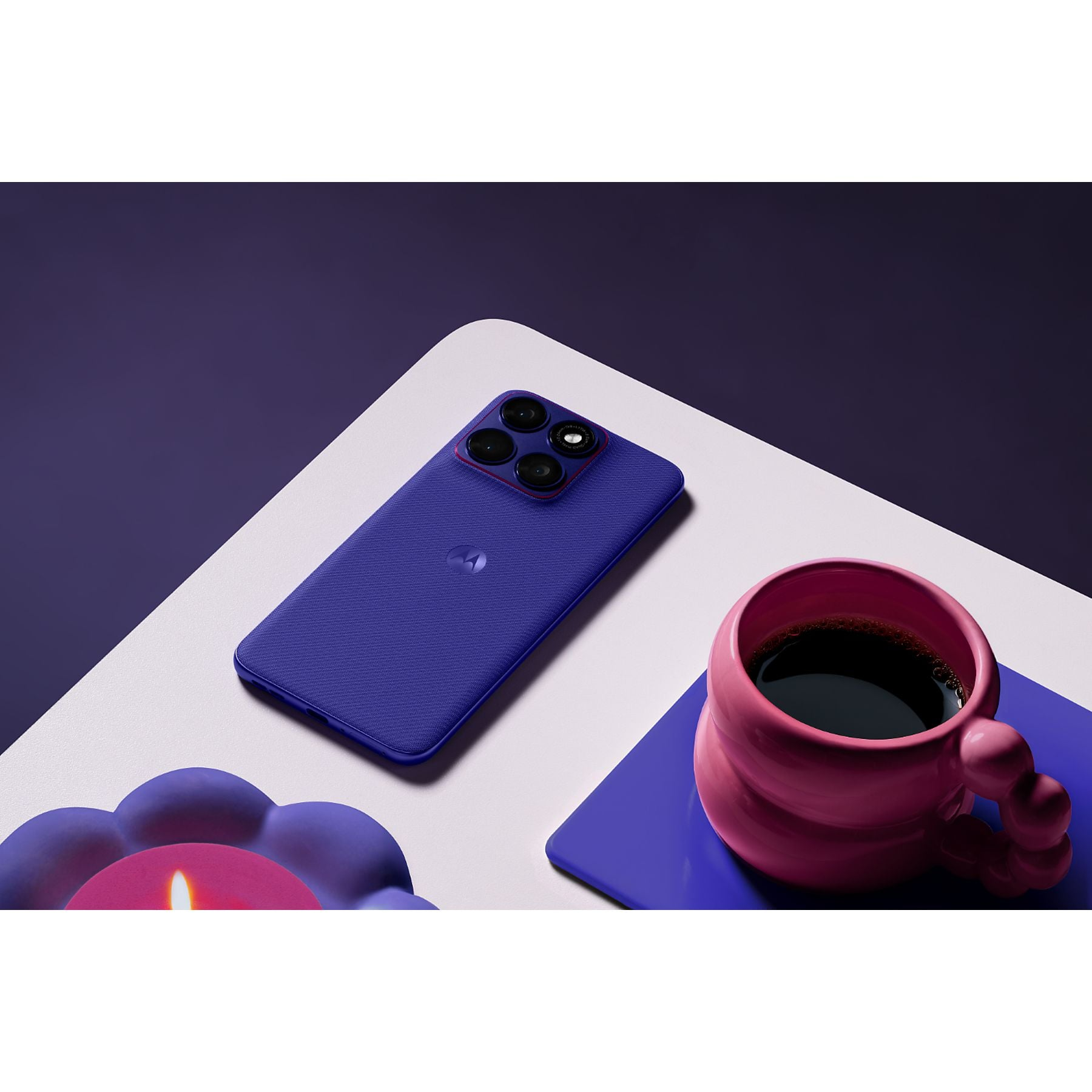 Ein violetter Motorolla-Handy liegt neben einer rosa Tasse Kaffee.