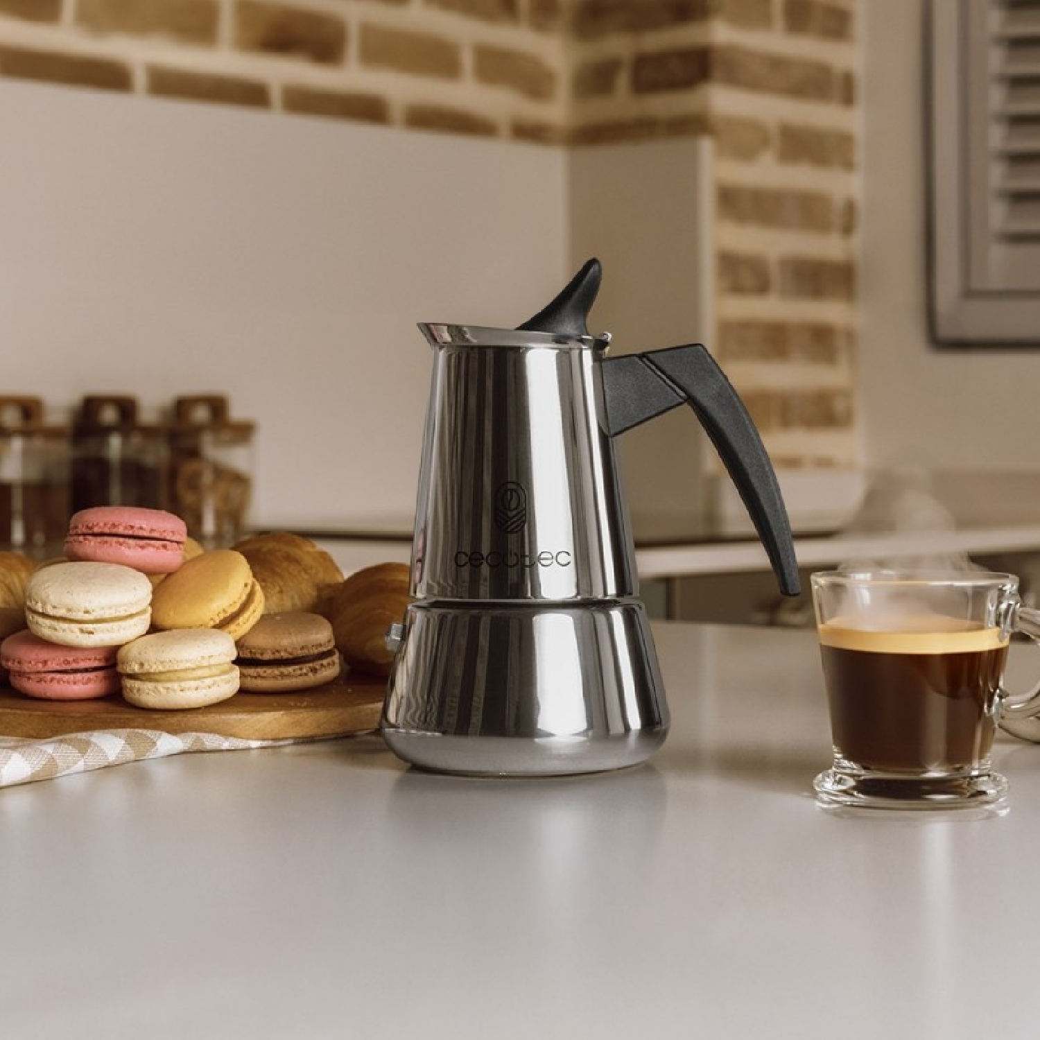 Una moka da caffè è accanto a macaron e caffè su un bancone.
