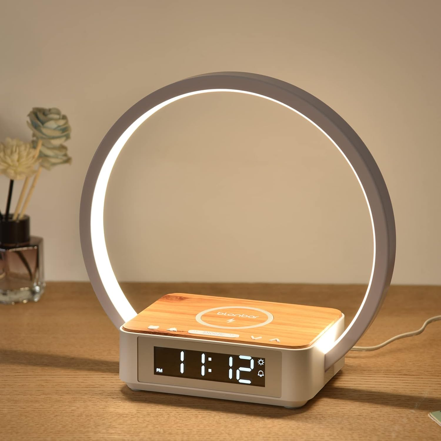 Ein moderner Nachttisch mit Ringlicht, Wecker und Holzoberfläche.