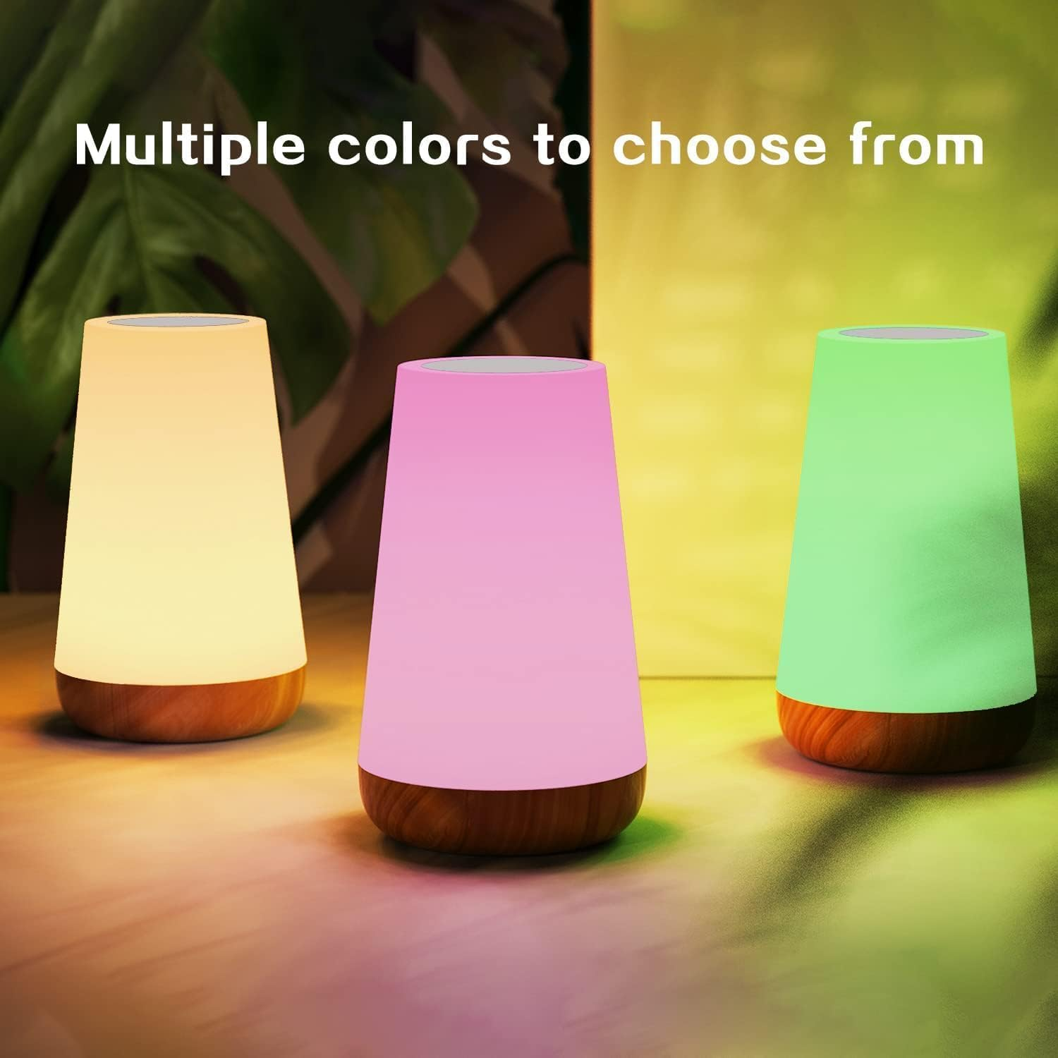 Drei Nachttischlampen in Gelb, Rosa und Grün auf einem Holztisch.