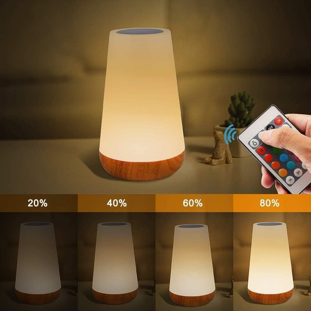 Eine Nachttischlampe mit Holzsockel wird mit einer Fernbedienung gesteuert.