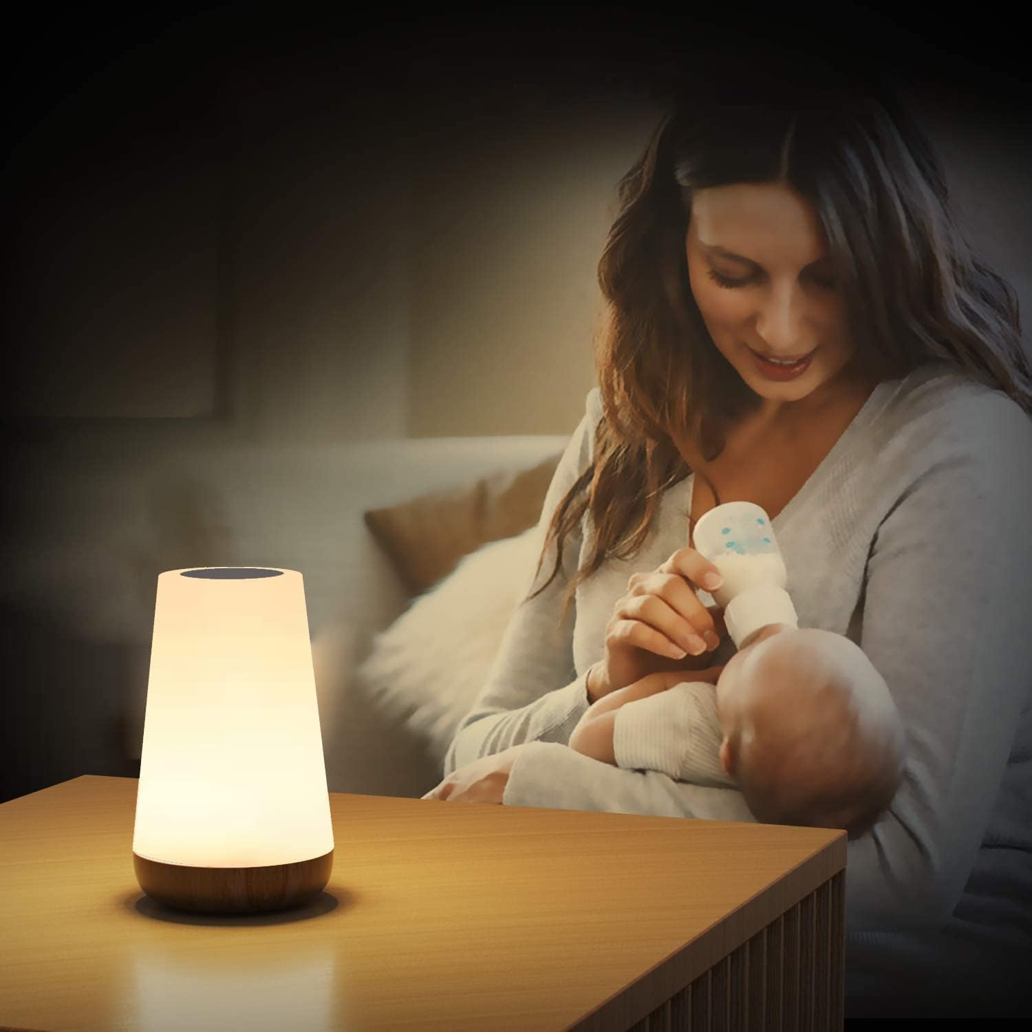 Eine Frau füttert ein Baby mit einer Flasche neben einer beleuchteten Lampe.