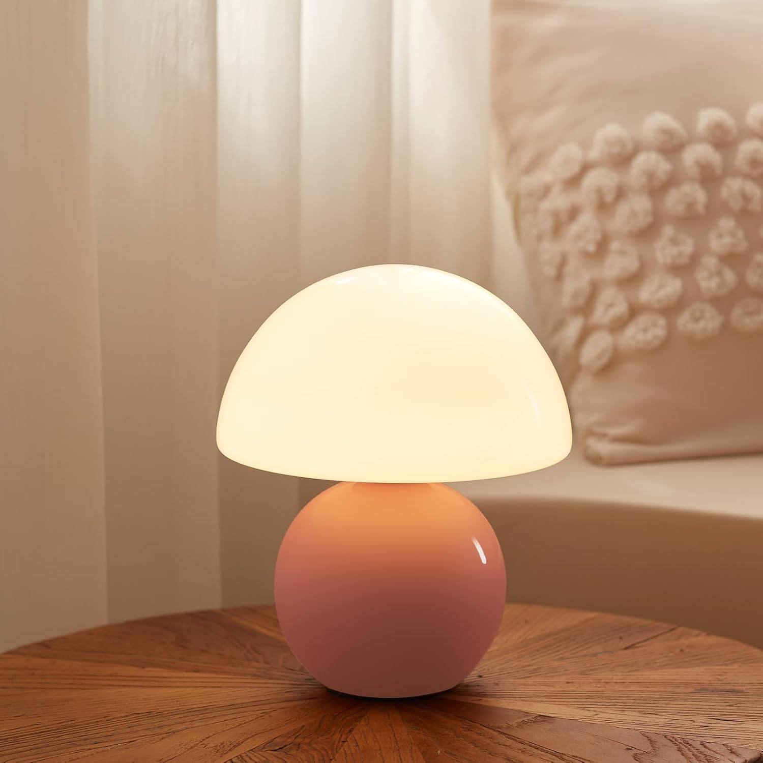 Eine rosa pilzförmige Lampe mit leuchtend weißer Oberseite steht auf einem Holztisch.