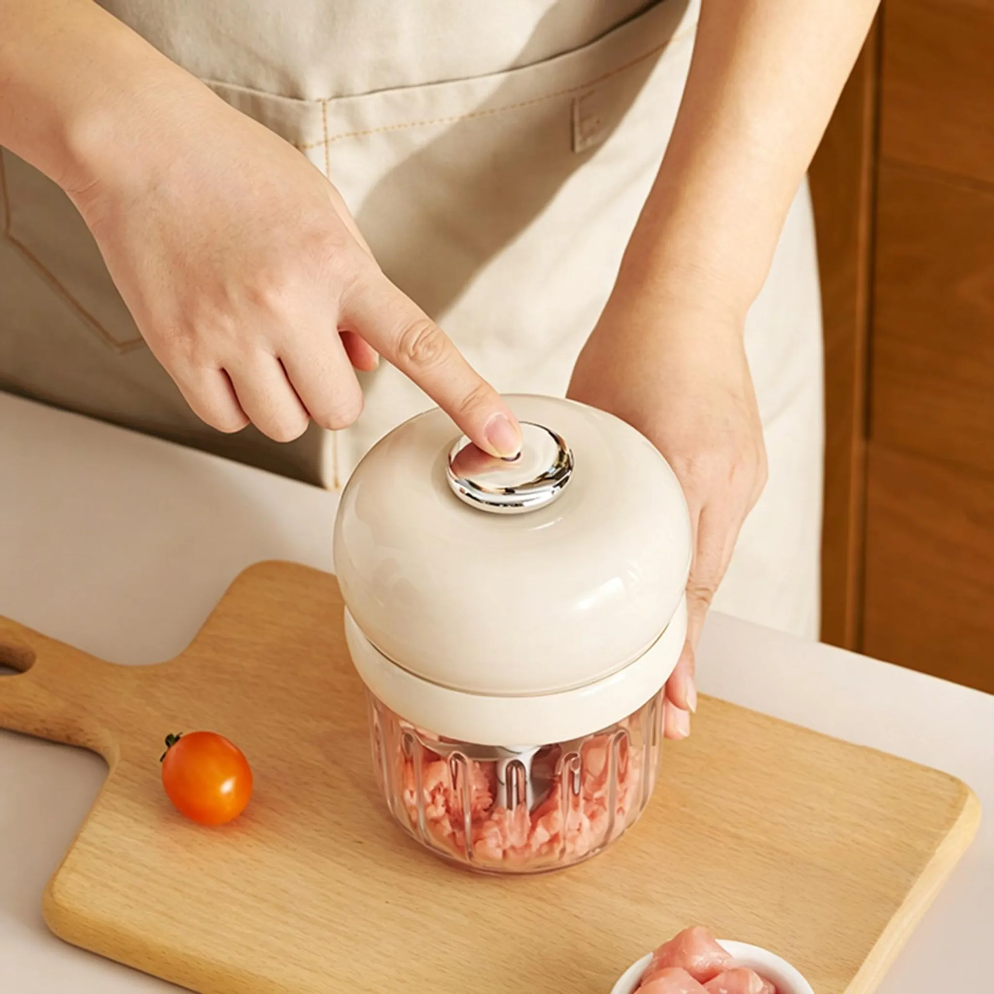 Eine Person drückt einen Knopf auf einem cremefarbenen Mini-Hacker, gefüllt mit gehacktem Fleisch.