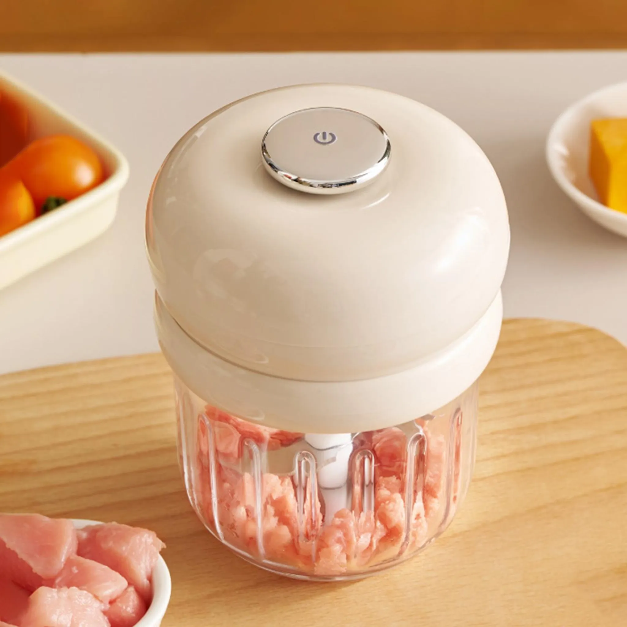 Ein cremefarbener Mini-Zerkleinerer mit transparentem Behälter, gefüllt mit gehacktem Fleisch.