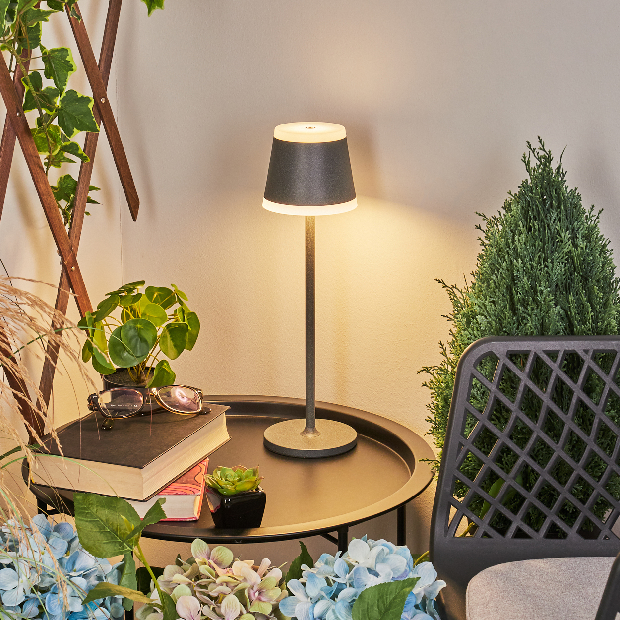 Ein Tisch mit Lampe, Buch und Pflanzen auf einem Balkon.