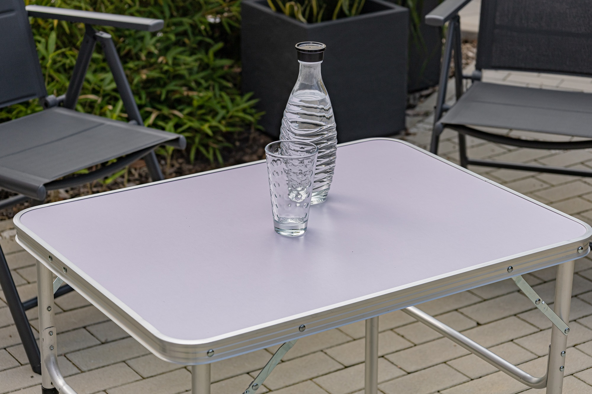 Ein Tisch mit einer Wasserflasche und einem Glas darauf, im Freien.