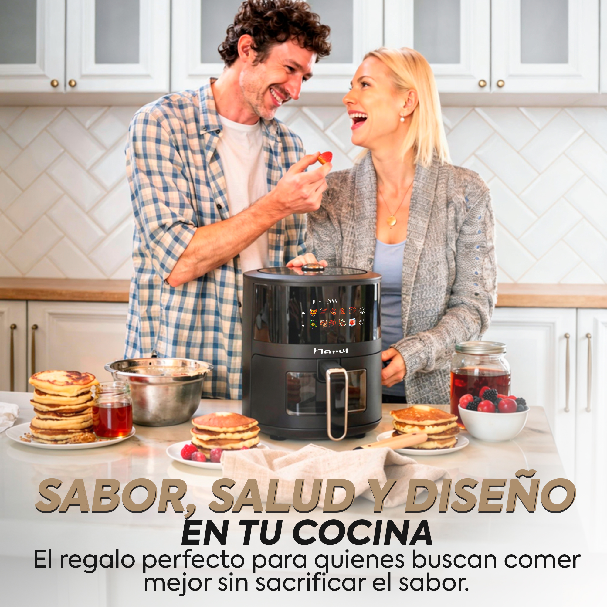 Pareja en una cocina con freidora de aire y tortitas. Hombre alimentando a mujer con fresa.