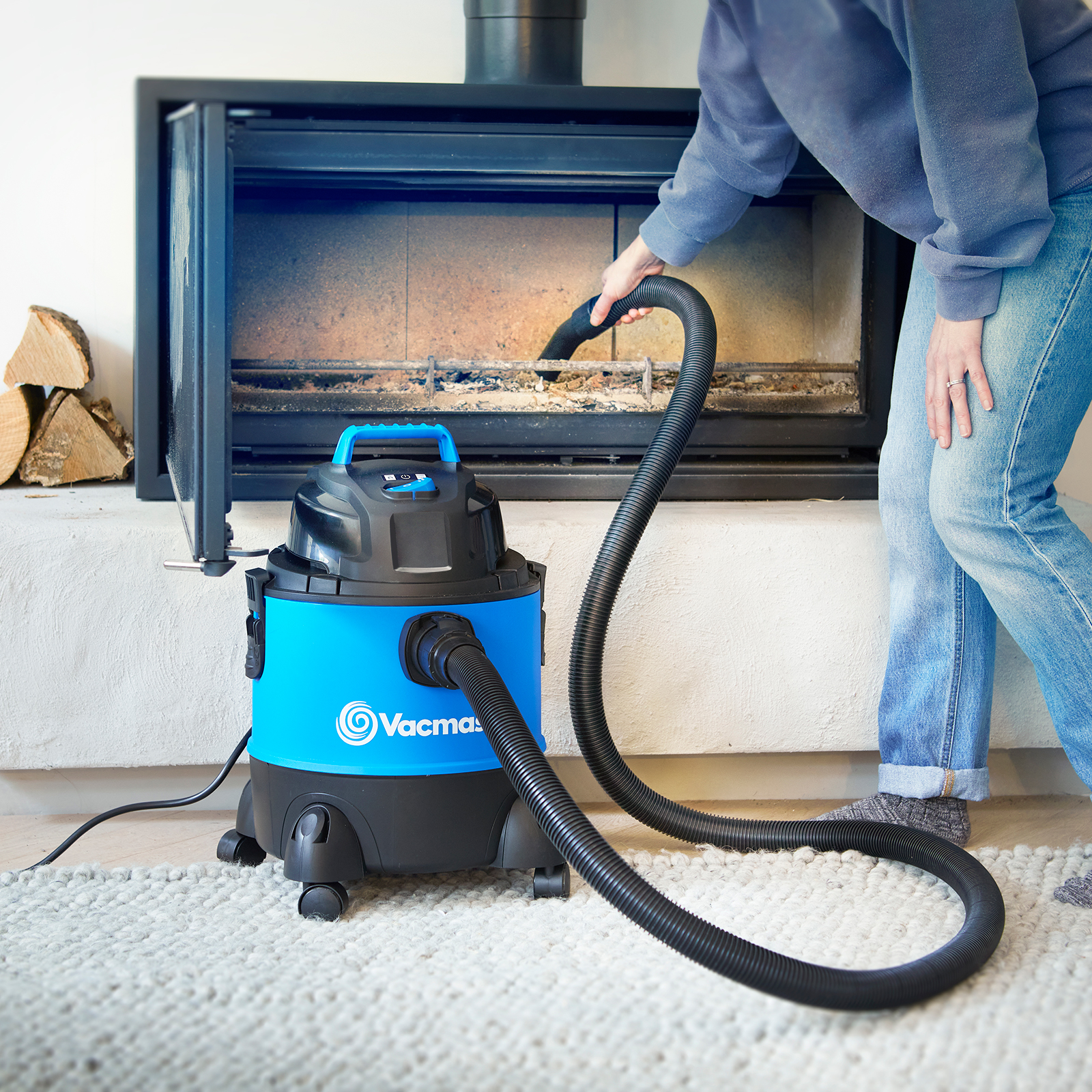 Eine blaue Nass-/Trockensaugmaschine reinigt einen Kamin, während eine Person daneben steht.