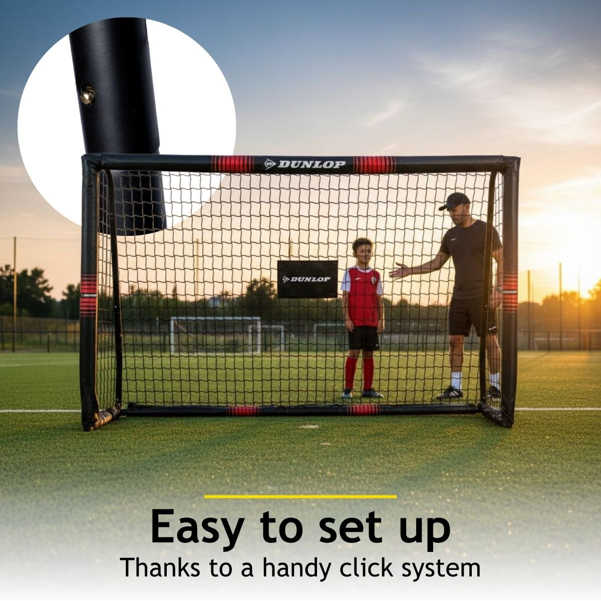 A man and a boy stand in front of a soccer goal on an artificial turf field.