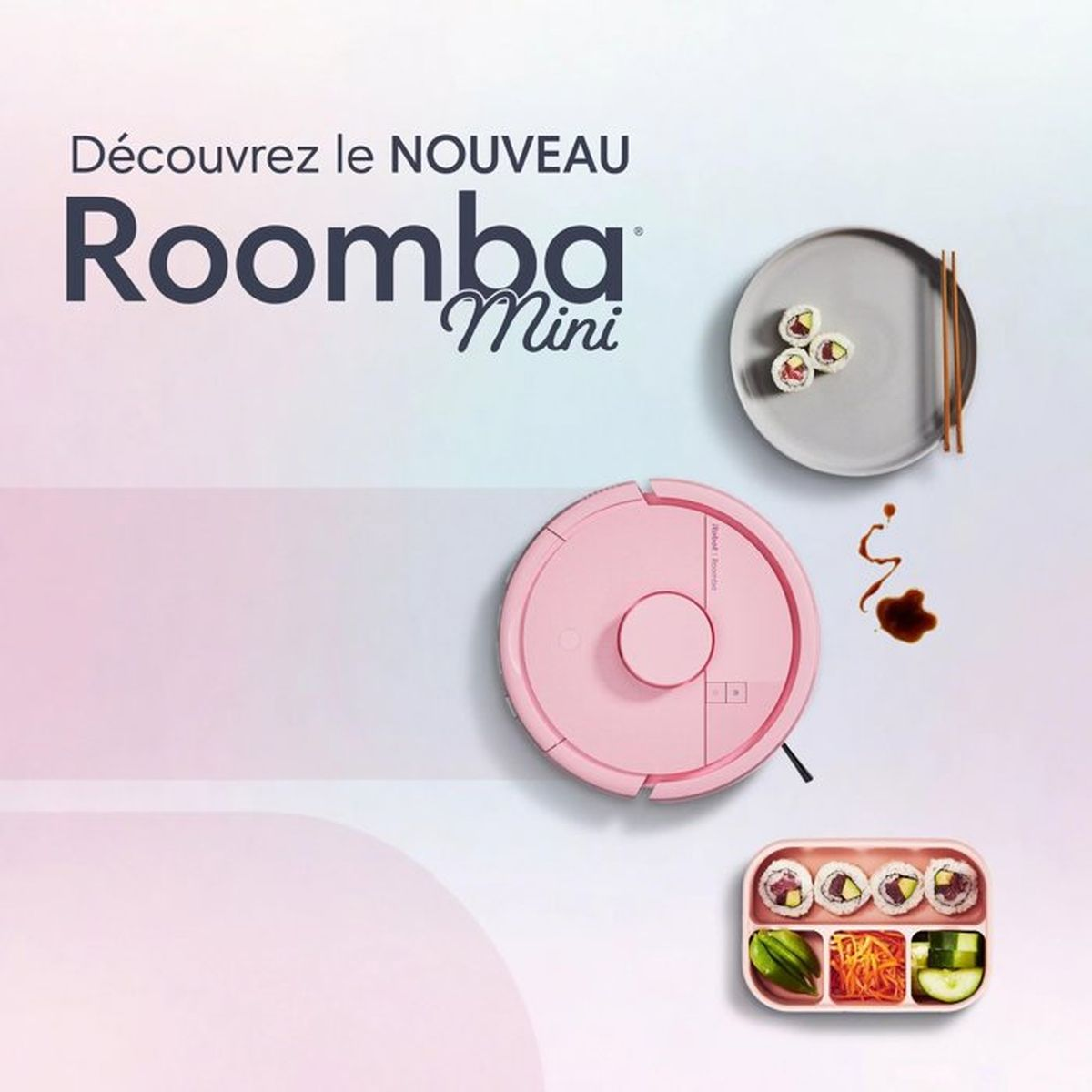 Un robot aspirapolvere rosa accanto a sushi e salsa di soia su sfondo chiaro.
