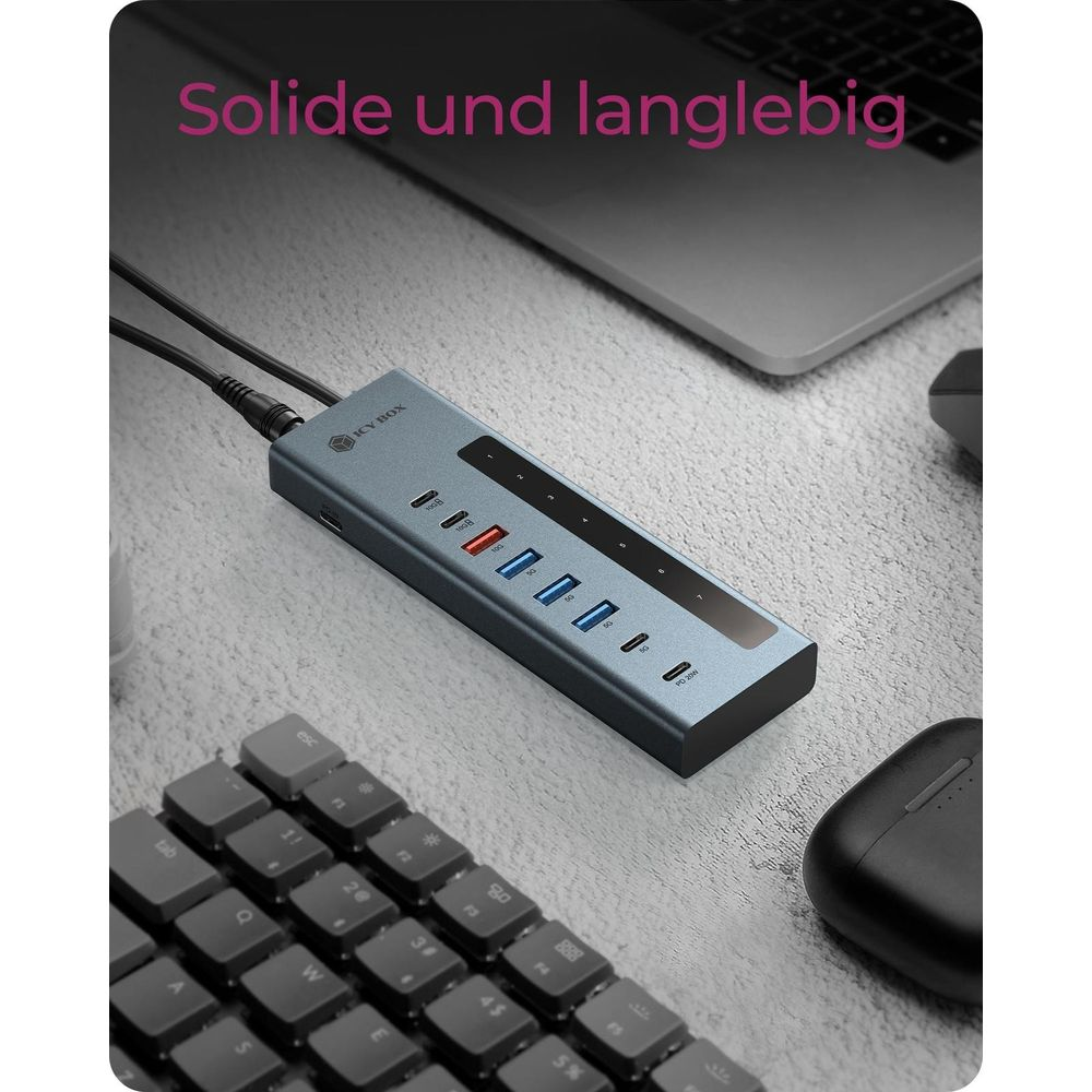 Grauer ICY BOX USB-C Hub mit mehreren Anschlüssen auf einem Schreibtisch neben einer Tastatur.