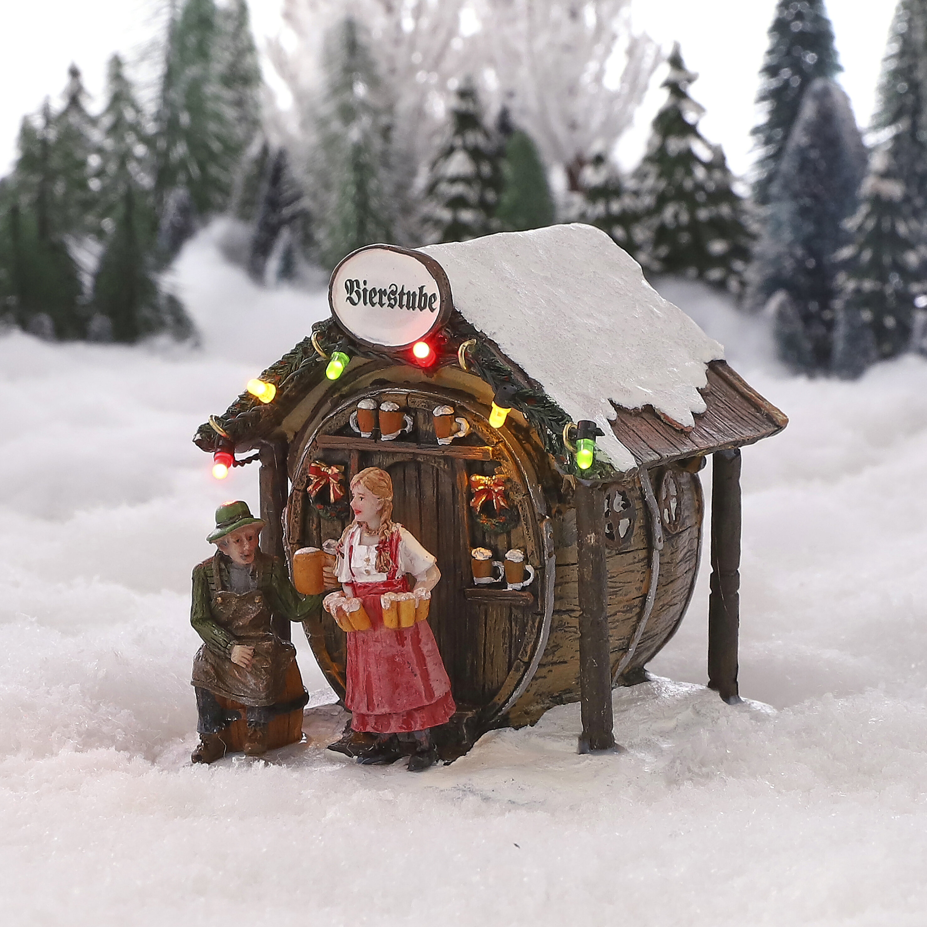 Miniatuur Bierstube huis in sneeuw met figuren, versierd met lampjes.