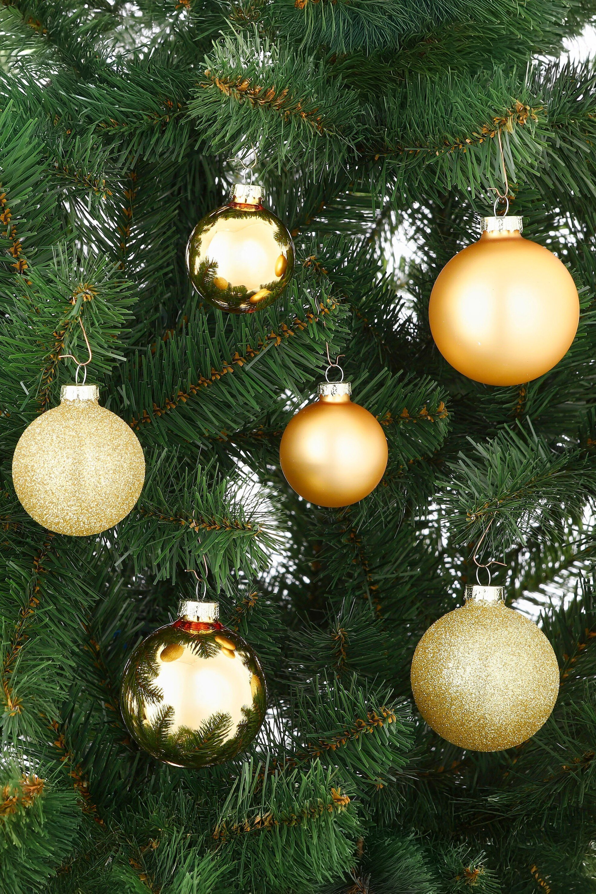 Gouden kerstornamenten hangen aan een groene kerstboom.