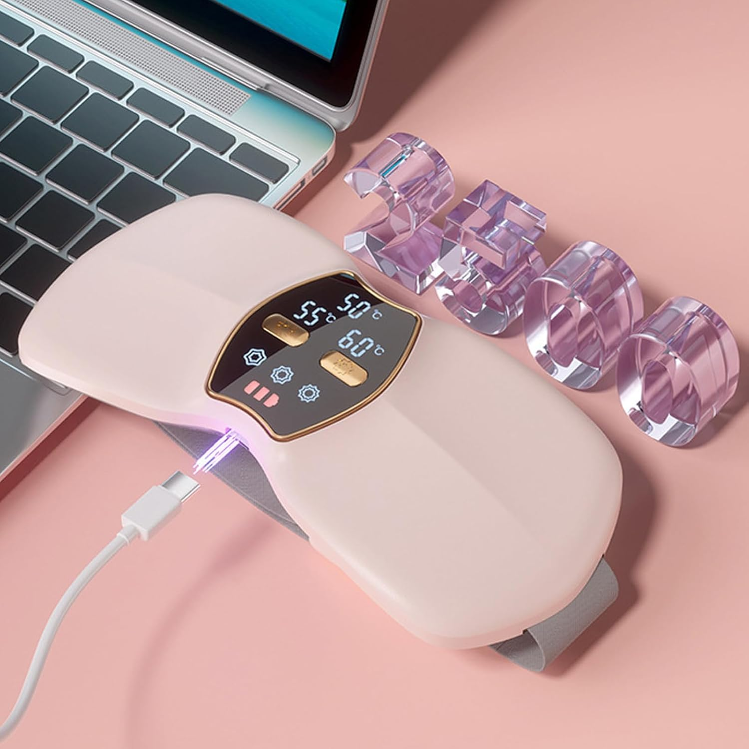Ein rosa Gerät mit eingestecktem USB-C-Kabel neben einem Laptop und Acrylhaltern.