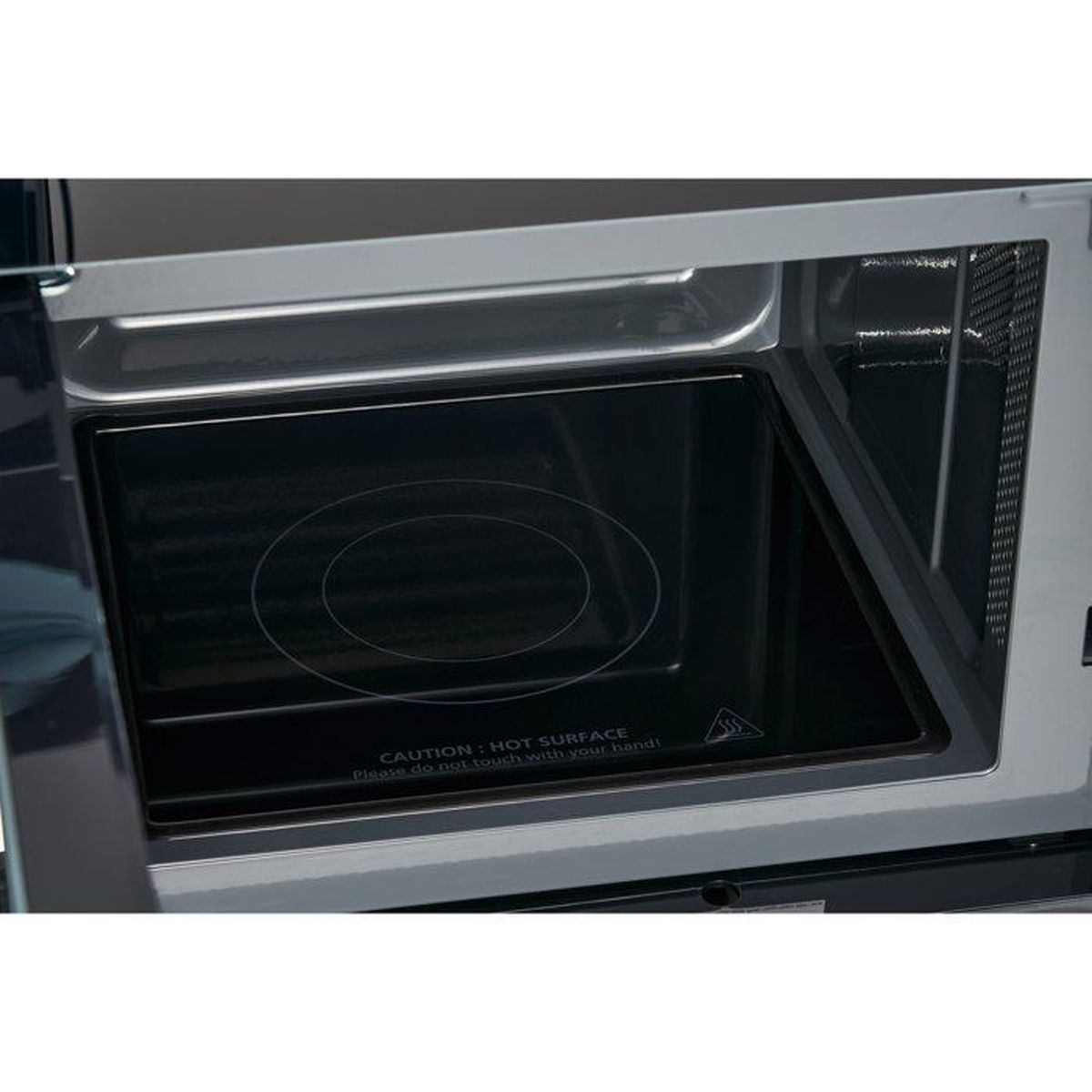 Interno di un forno a microonde con piatto girevole nero e cartelli di avvertimento.