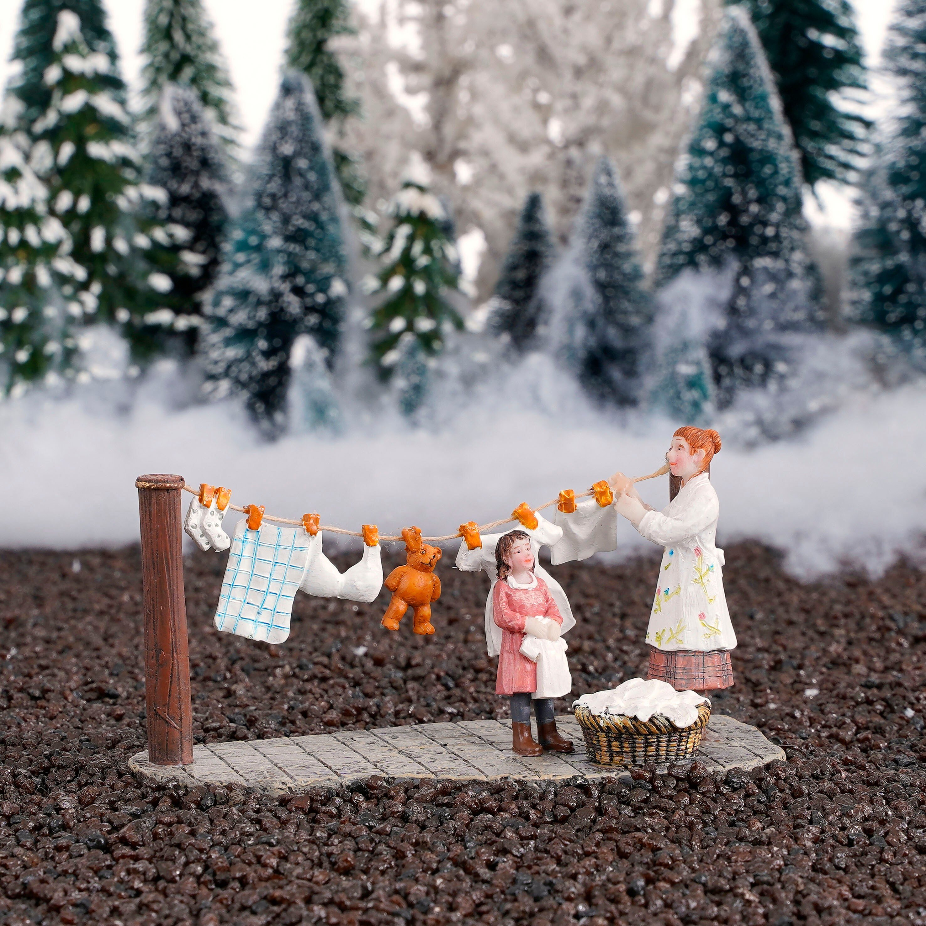 Twee figuren in een winterse bosrijke omgeving hangen wasgoed aan een lijn.