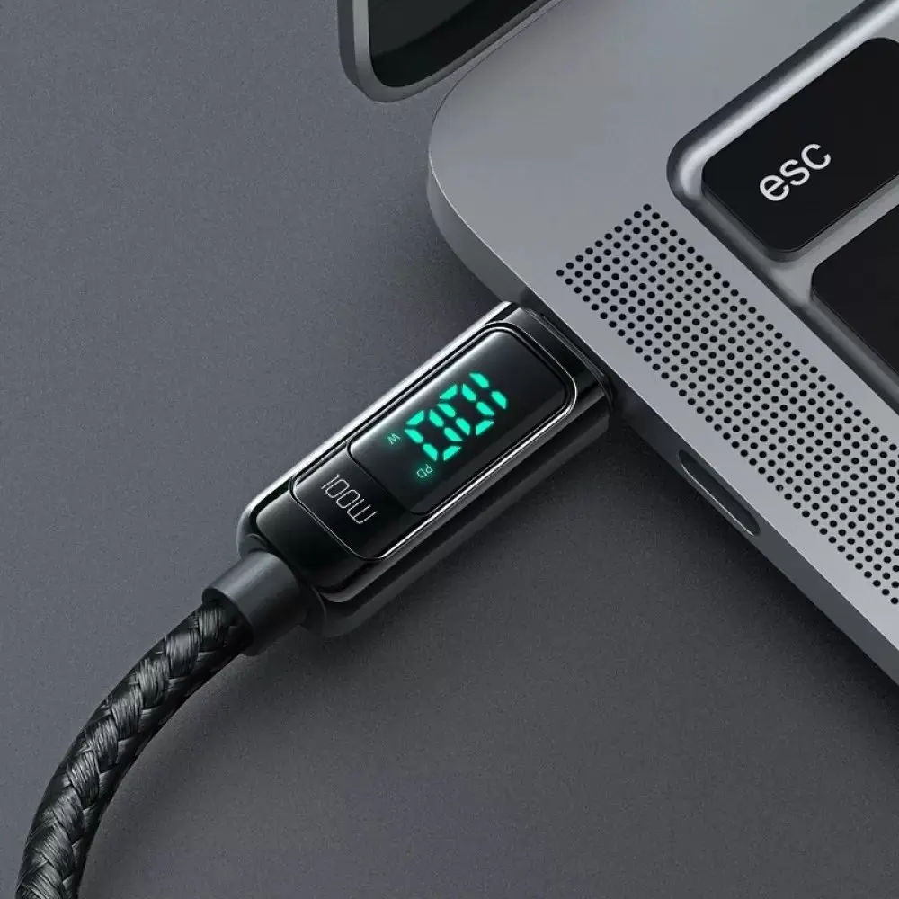 Bir dizüstü bilgisayara takılı dijital ekranlı siyah USB-C kablosu.