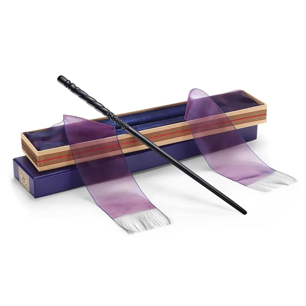 Una varita negra descansa sobre una caja morada y de color madera con cinta morada.