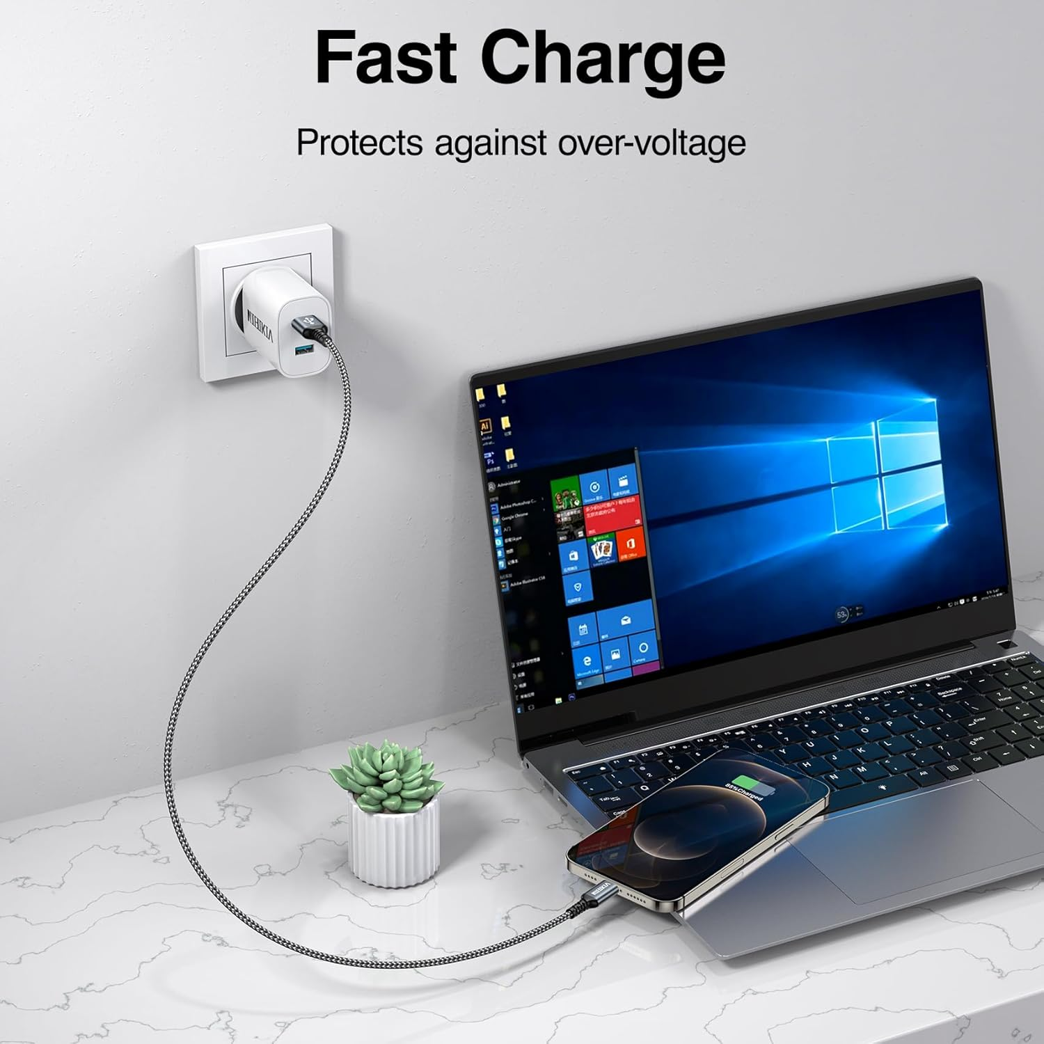 Ein Netzteil lädt ein Handy an einem Laptop, ein kleiner Topf mit Sukkulente daneben.