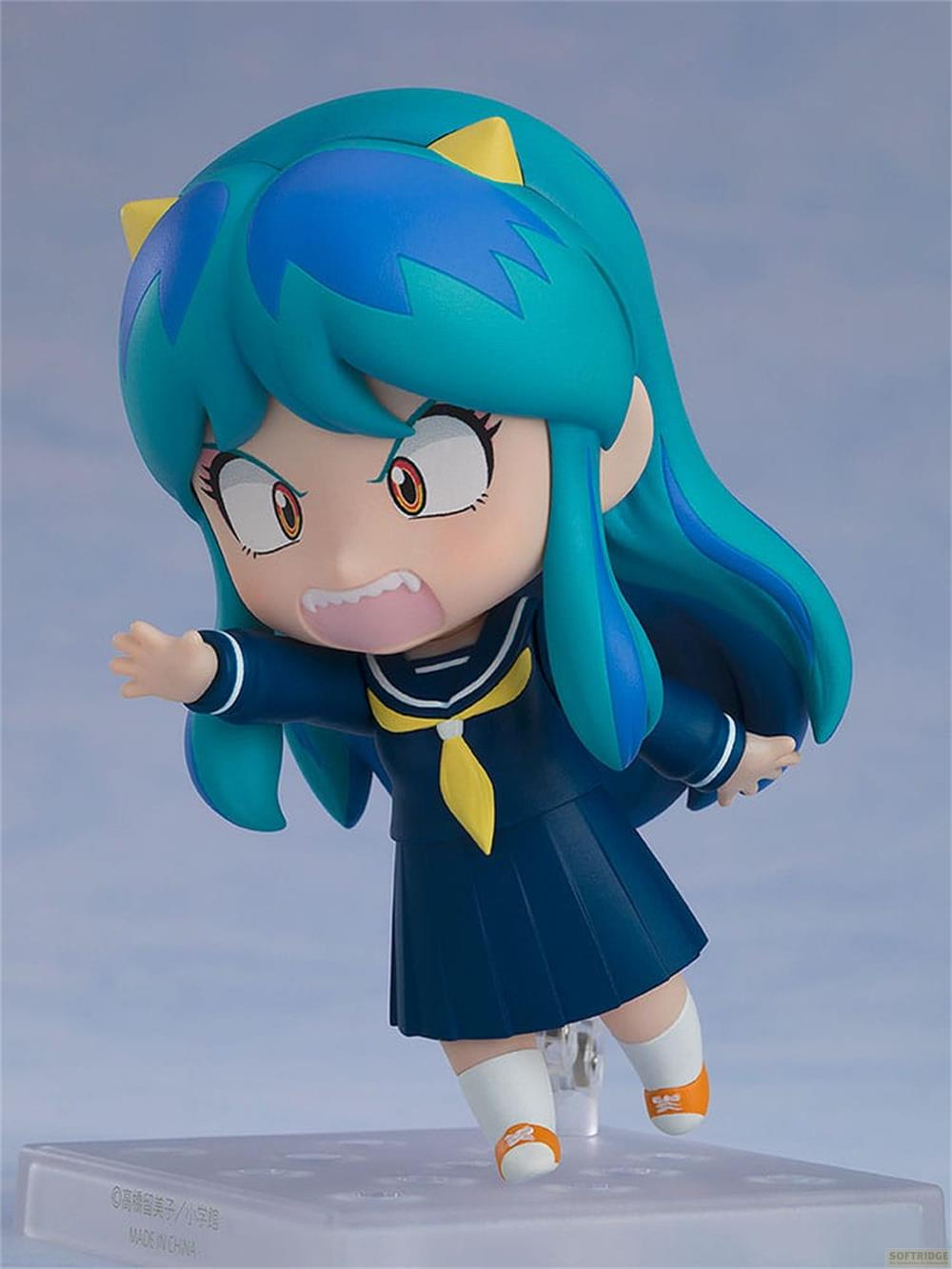 Figura chibi de anime con pelo turquesa, uniforme azul, corbata amarilla y calcetines blancos.