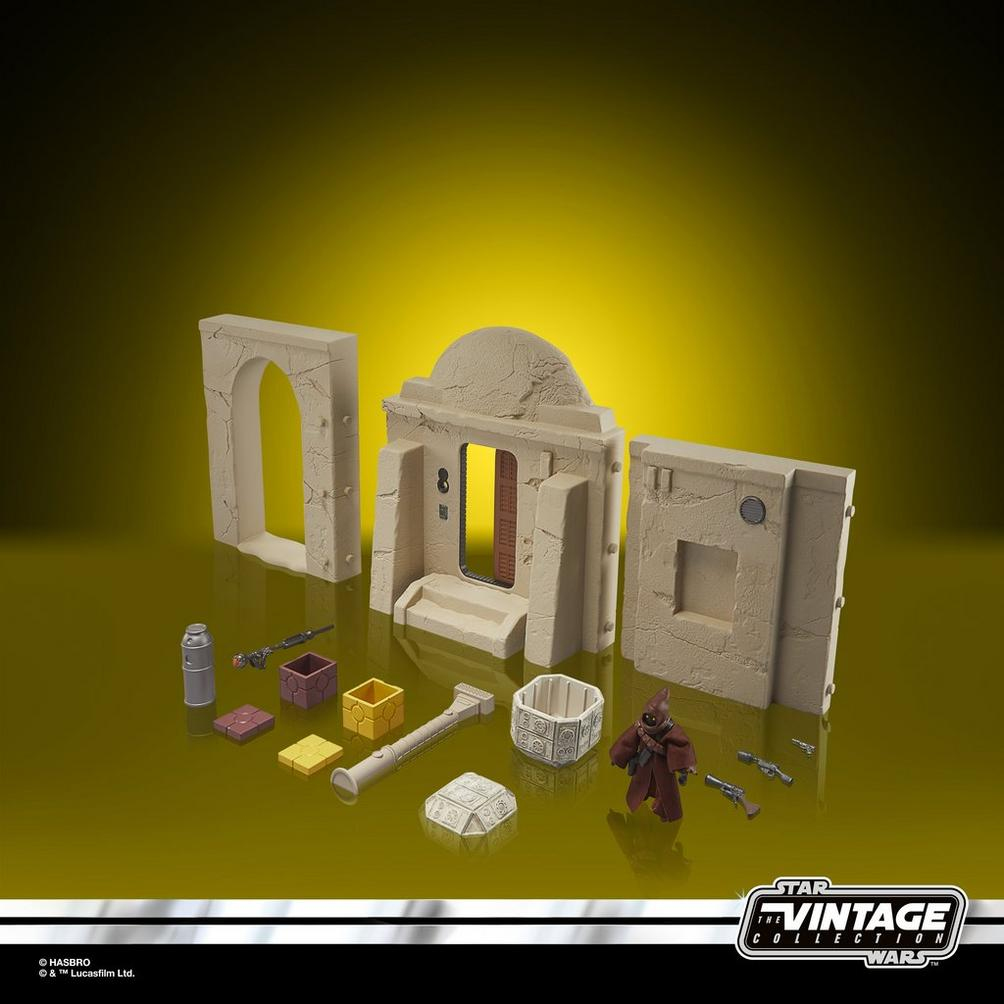 Juguetes de Star Wars: Edificios color canela, una figura Jawa y accesorios sobre fondo amarillo.
