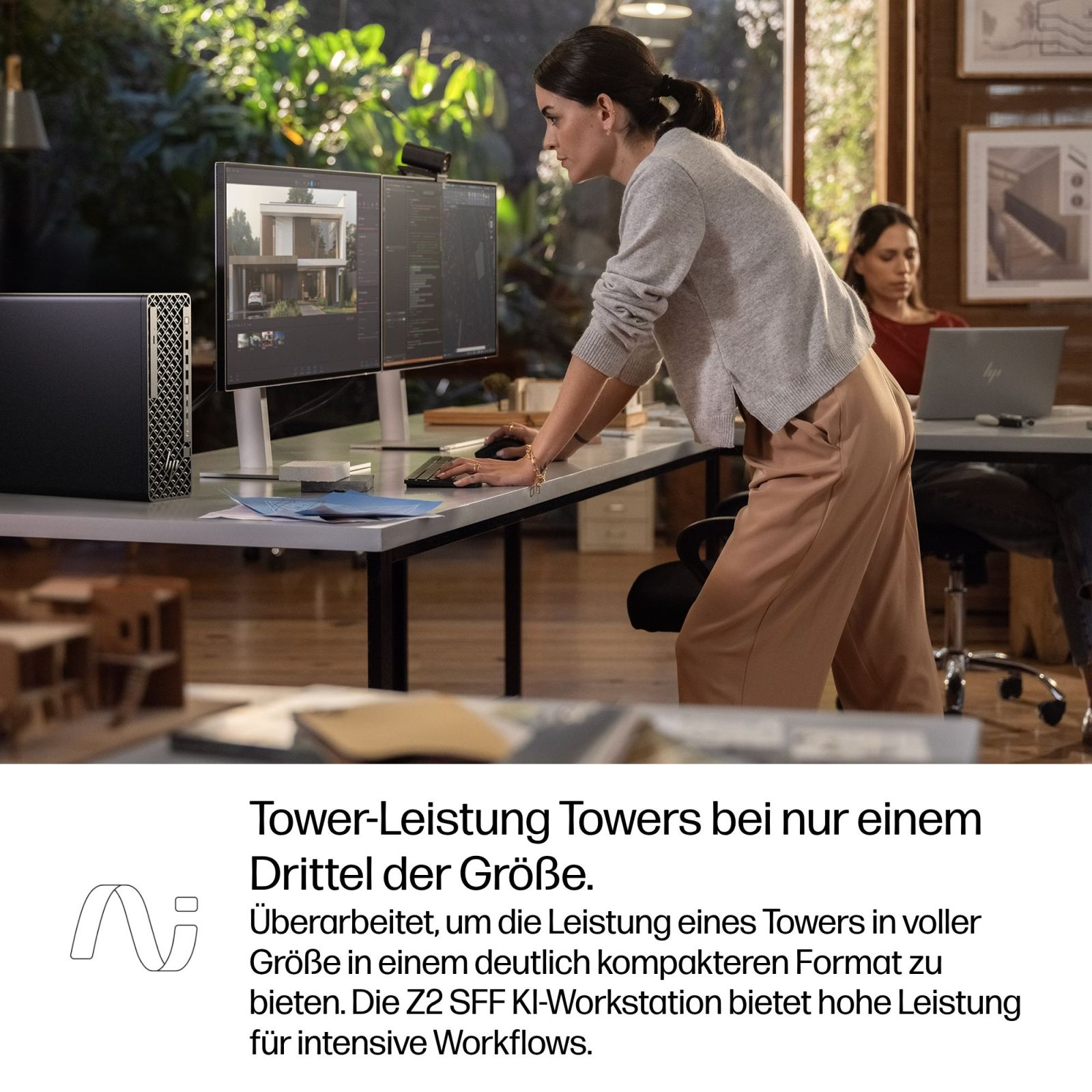 Donna lavora a due monitor con una torre PC nera accanto.