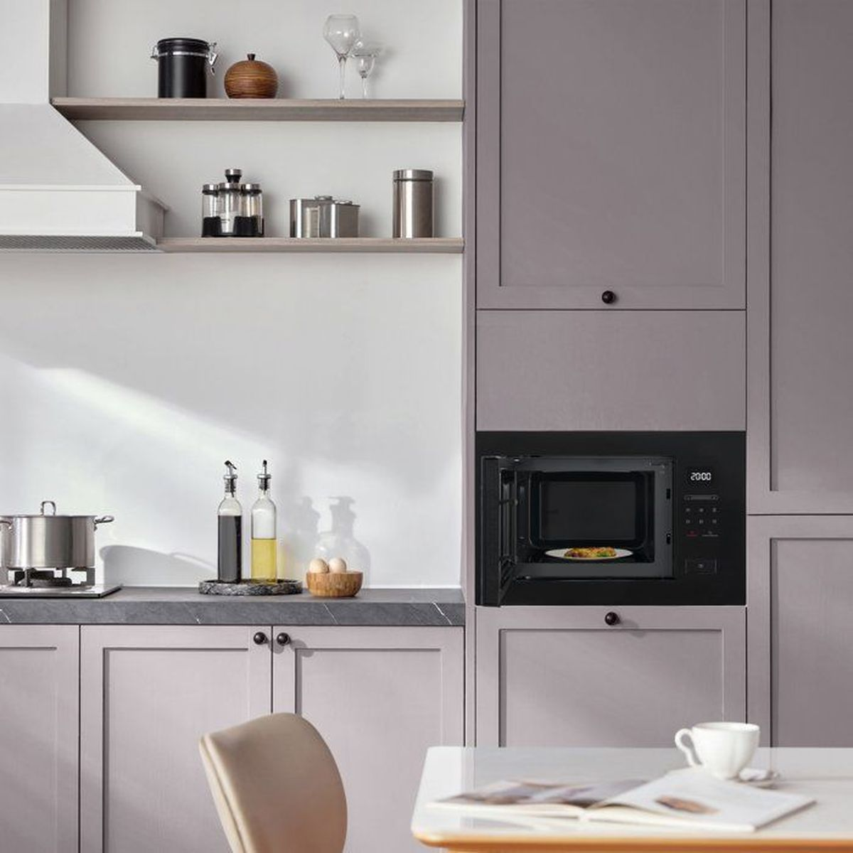 Una moderna zona cucina con microonde aperto e utensili.