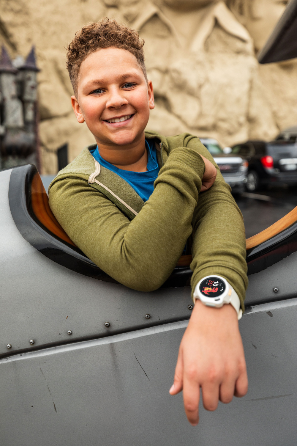 Ein Junge mit lockigem Haar sitzt in einem Flugzeugcockpit und lächelt.