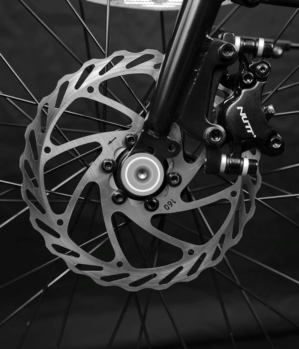 Primer plano de un freno de disco de bicicleta con rotor plateado y pinza negra.