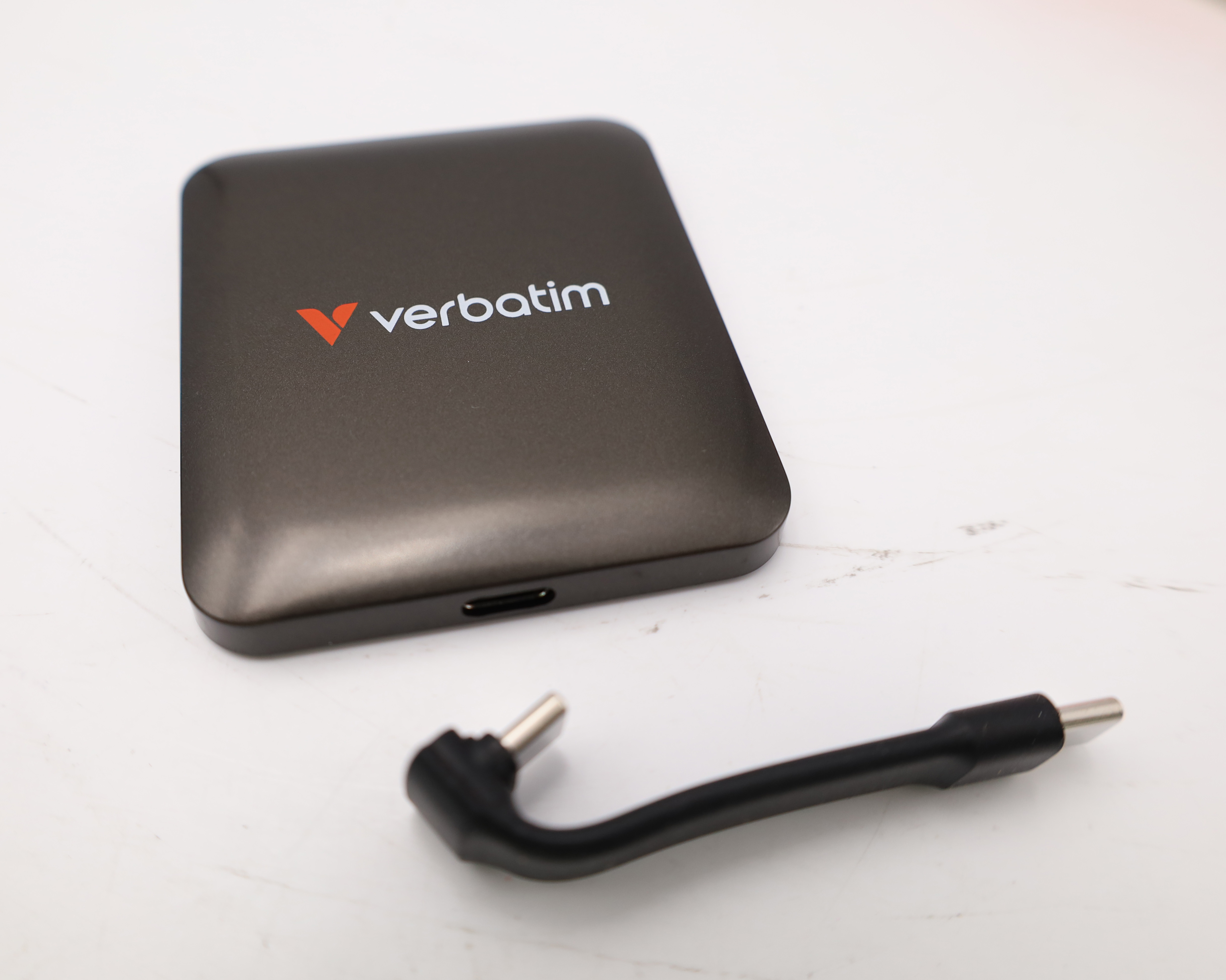 Eine graue Verbatim externe Festplatte mit schwarzem USB-Kabel auf weißem Untergrund.