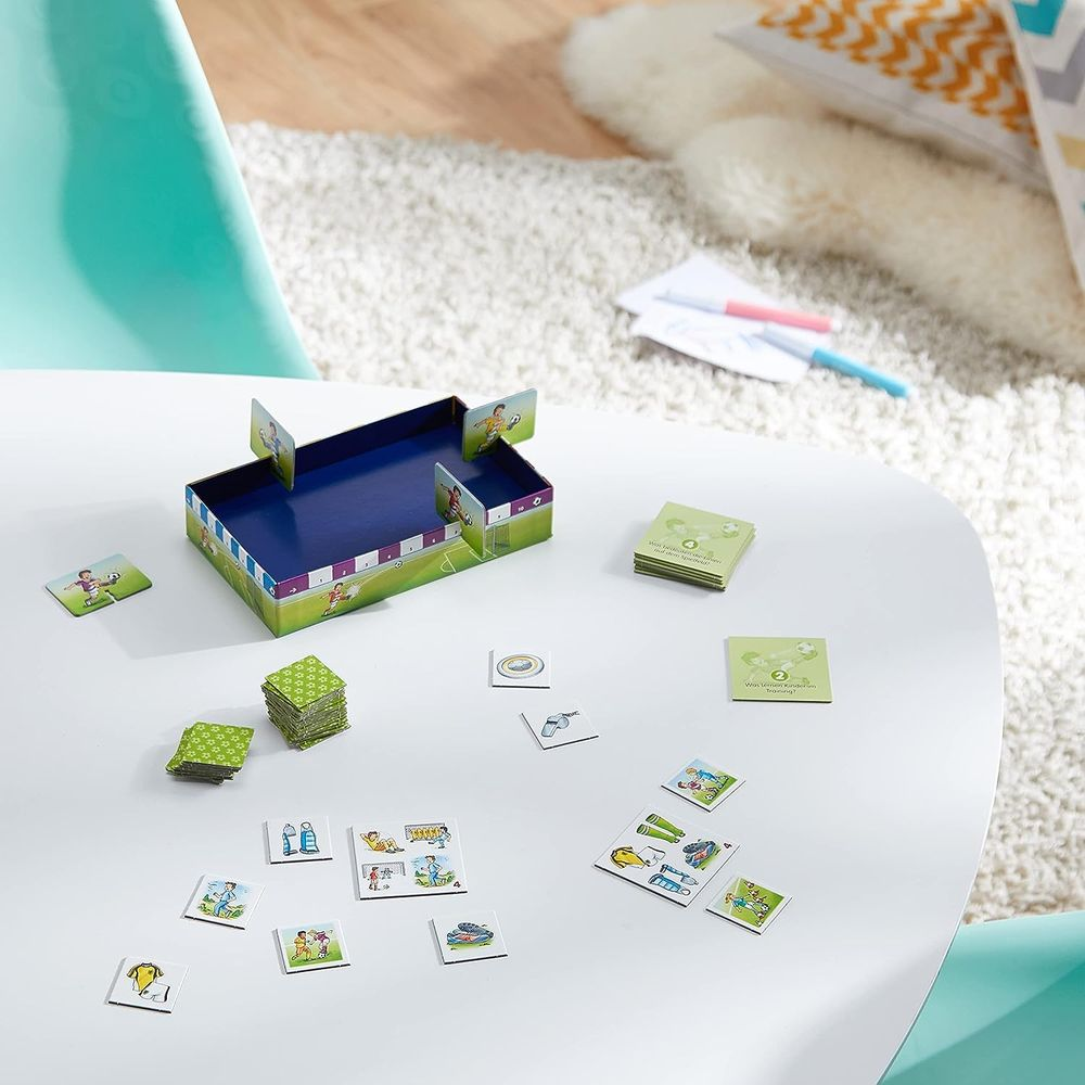 Fußballspiel-Brettspiel mit Karten und Spielfiguren auf einem weißen Tisch.