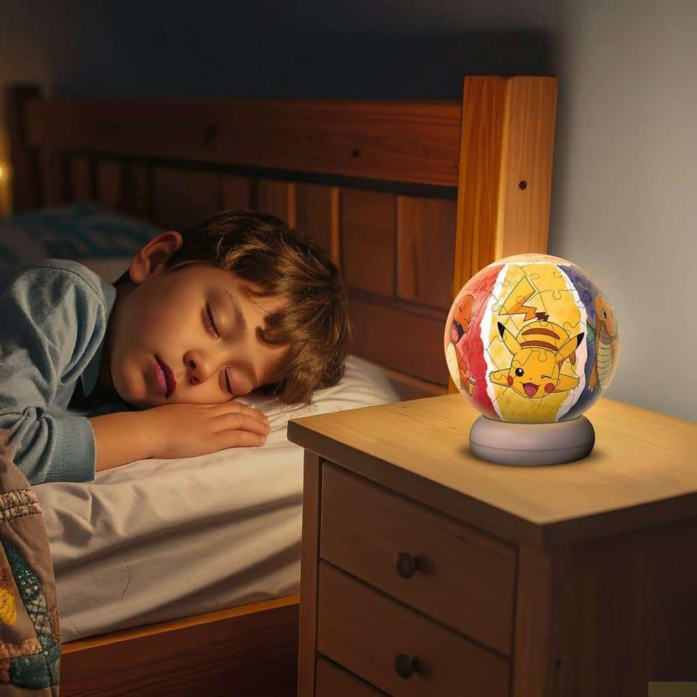 Un garçon dort dans son lit à côté d'une veilleuse Pikachu sur une table de chevet.