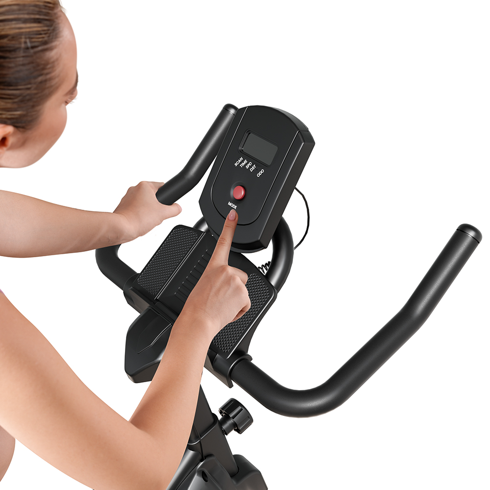 Una donna preme il pulsante della modalità sulla console di una cyclette.